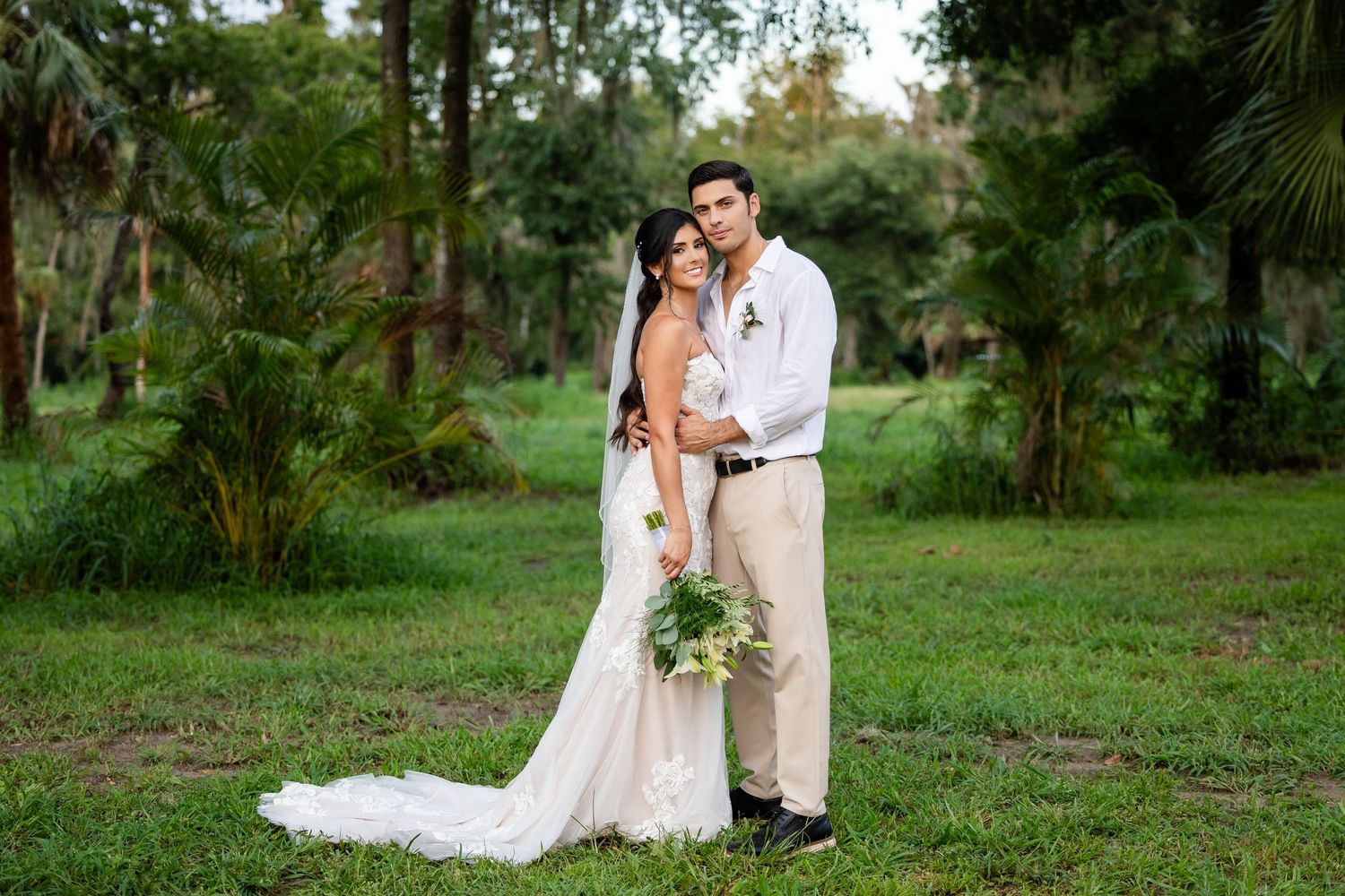 A romantic outdoor wedding scene with a couple sharing an intimate moment in a lush green garden setting.