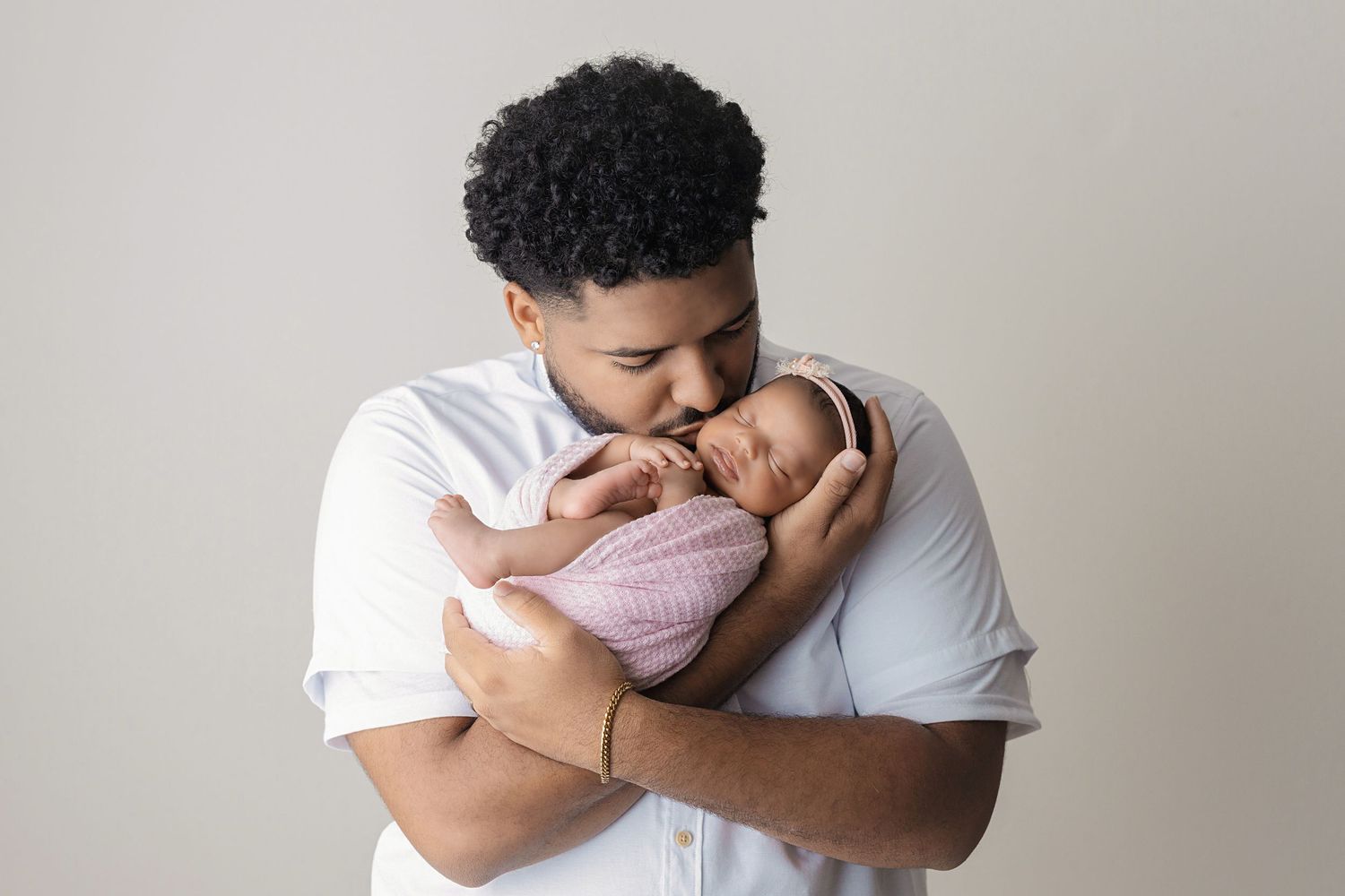 Tender moment between parent and newborn captured in minimalist studio setting.
