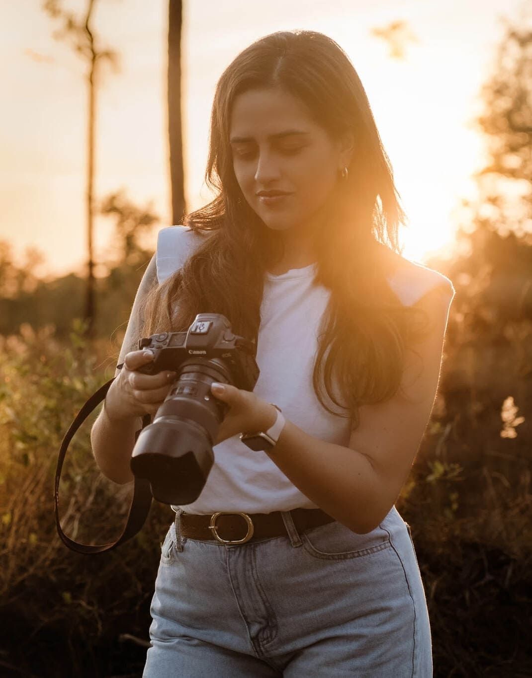 Photographer reviews images on camera display during beautiful sunset photoshoot in outdoor setting.