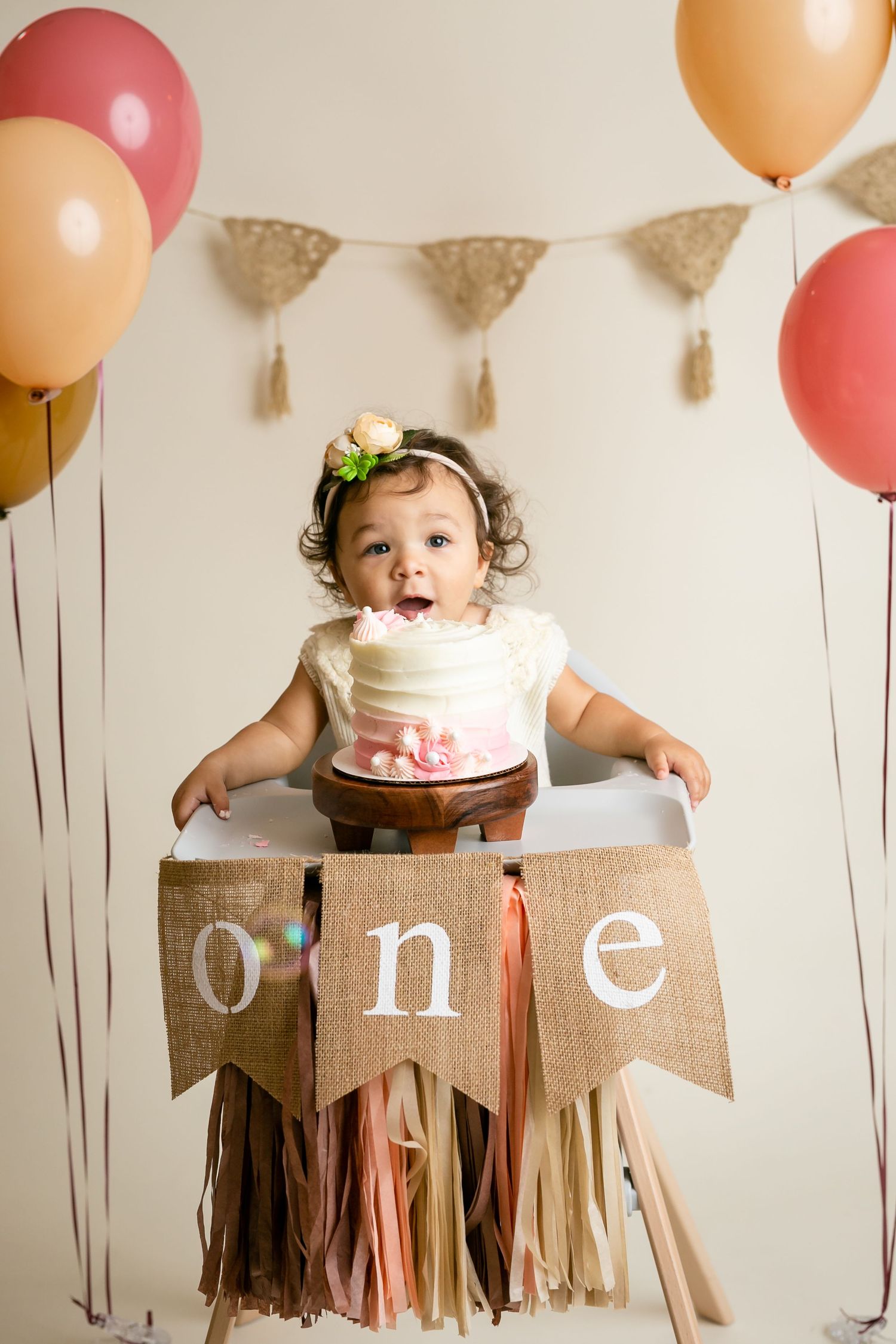First birthday celebration with decorated high chair, balloons and burlap banner.