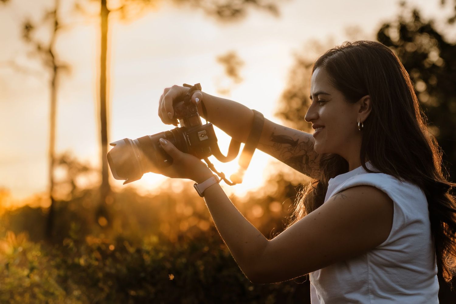 Silhouette of photographer checking camera settings during golden sunset.
