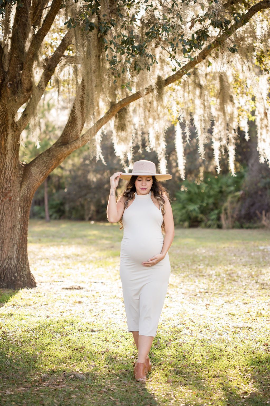 fotografa de embarazo en tampa mujer embarazada sombrero beige parque luz natural
