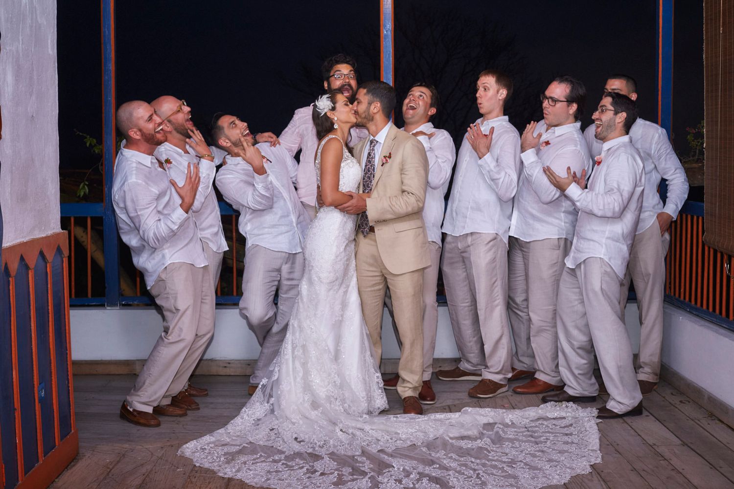 A wedding party poses for fun group photos showing playful and candid moments on a wooden deck.