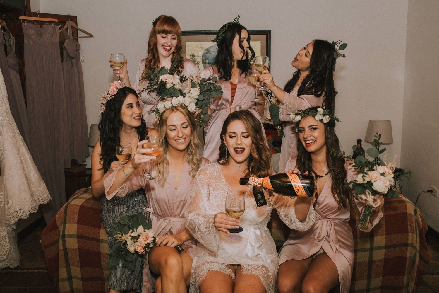 Wedding party wearing blush pink dresses celebrate together with drinks at a reception.
