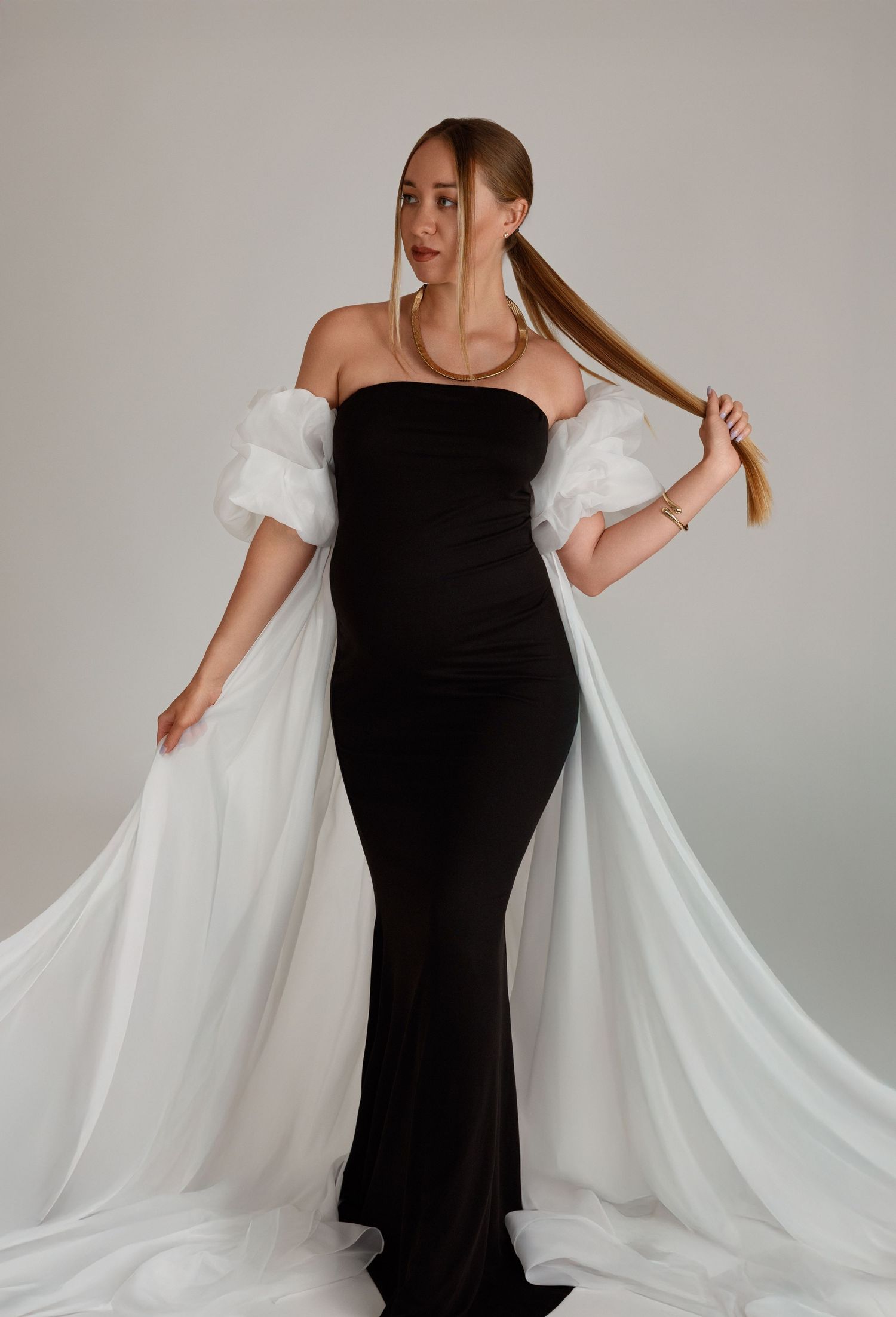 Maternity session in Laval, Montréal — pregnant woman in a black gown with white tulle sleeves.