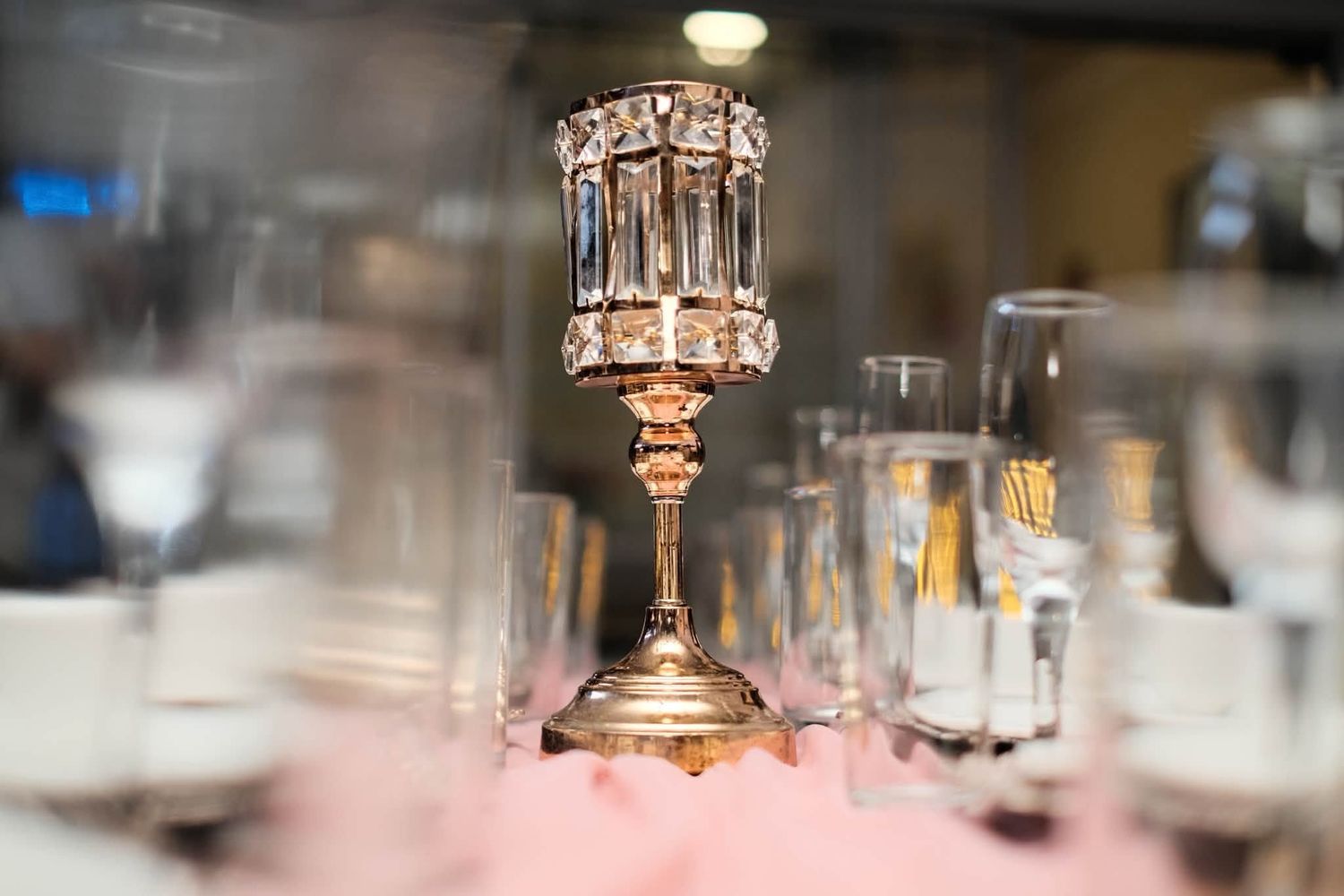 Ornate gold and crystal candelabra centerpiece surrounded by elegant glassware on a decorated table.