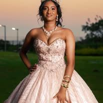 Young woman in a beaded strapless ball gown posing outdoors at sunset for a formal occasion.