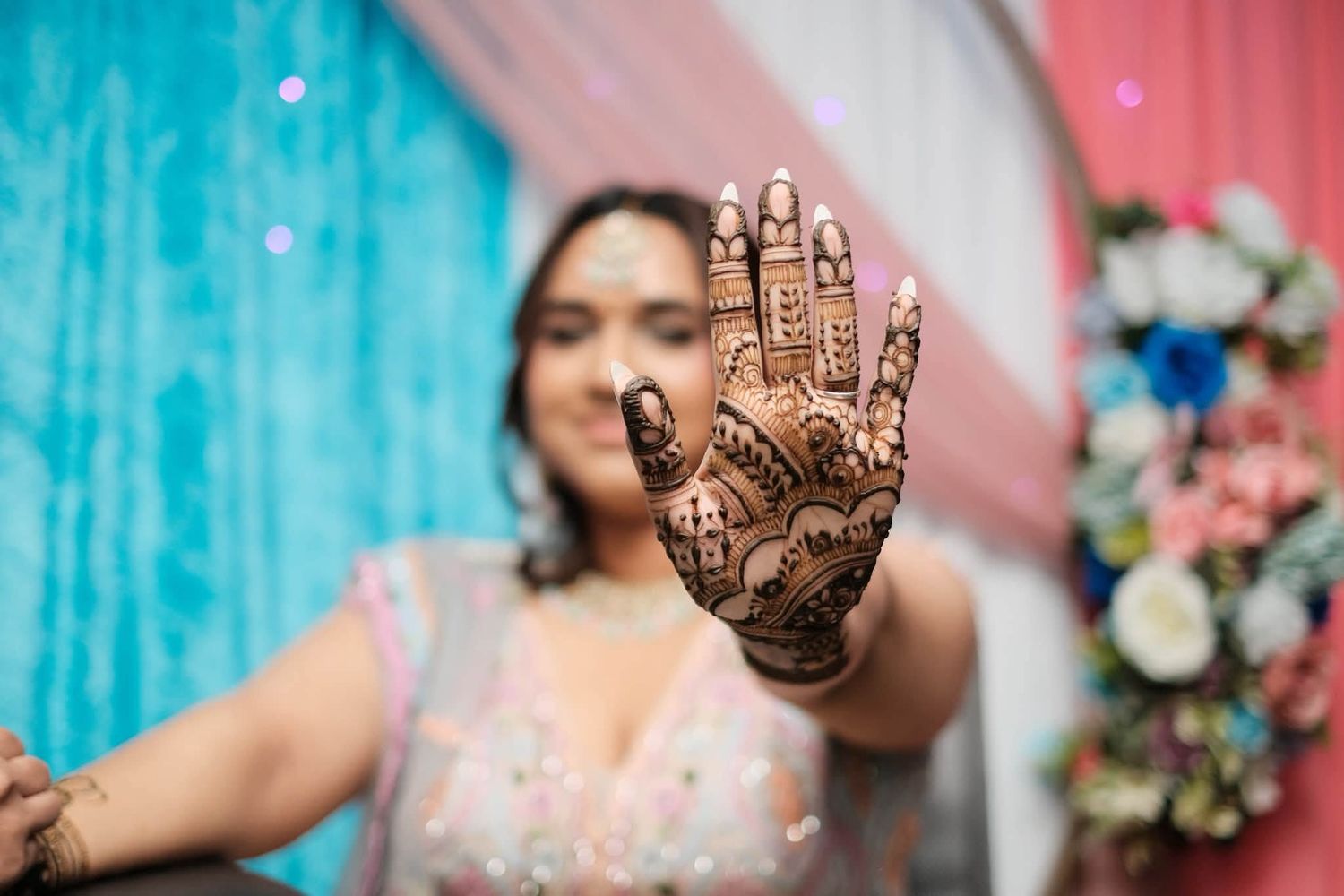 A bride showcases intricate henna mehndi design on her hand at a traditional Indian wedding ceremony.