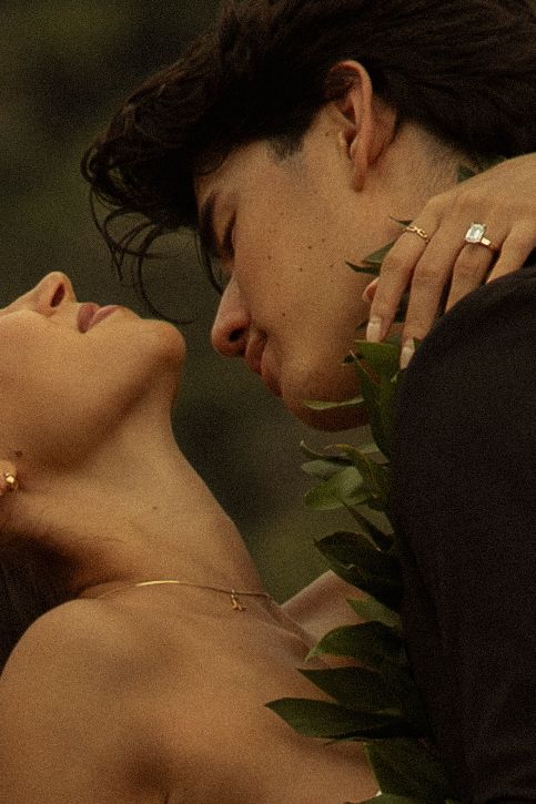 Intimate close-up of a bride and groom almost kissing surrounded by tropical greenery.