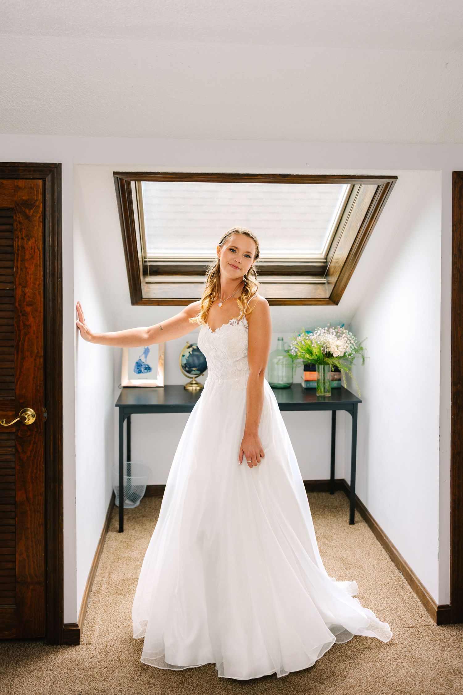 A bride in a flowy white wedding gown spins and twirls in a bright indoor hallway, showing off the dress's movement.