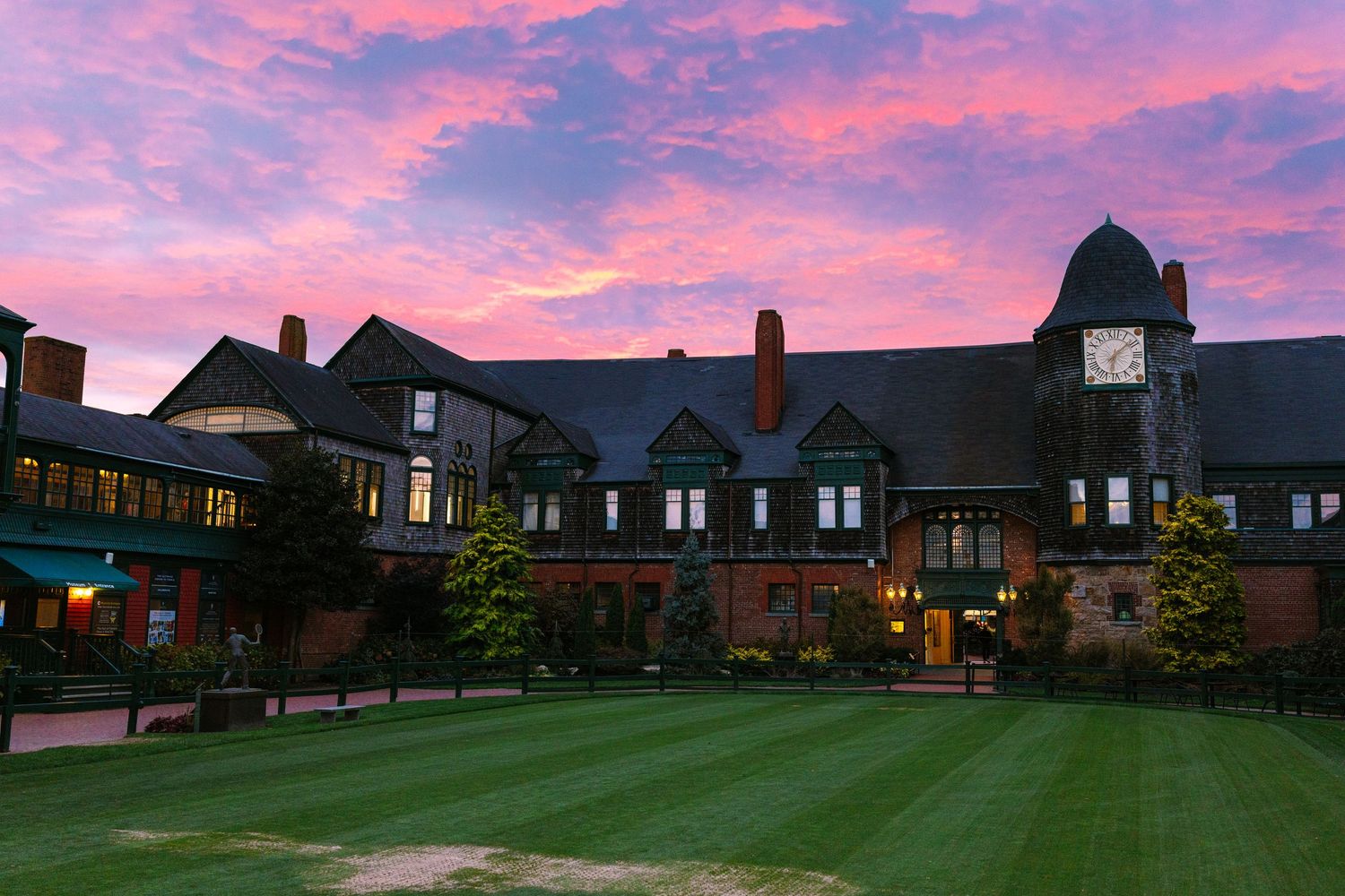 Historic International Tennis Hall of Fame brick building with Tudor-style architecture set against a dramatic purple and pink sunset sky.