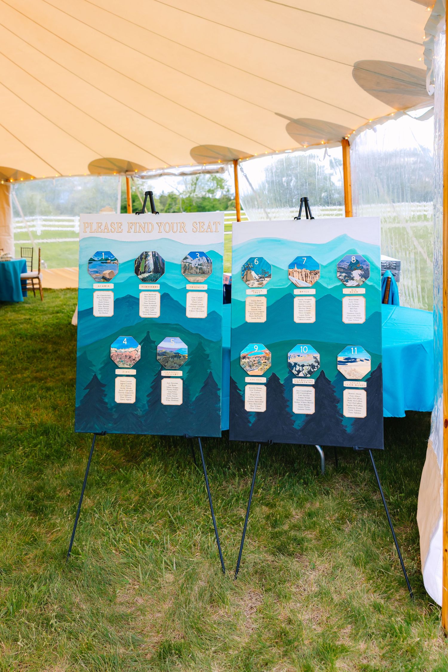 Blue seating chart display board with penguin decorations set up under a white tent at an outdoor event.