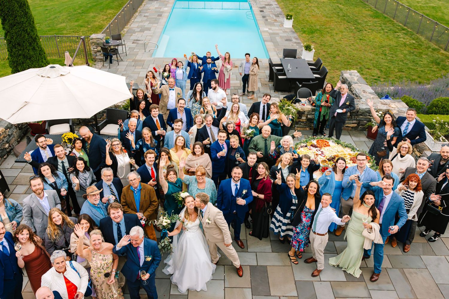 Aerial view of a large wedding reception gathering on a stone patio next to an outdoor swimming pool on a cloudy day in Stonington CT
