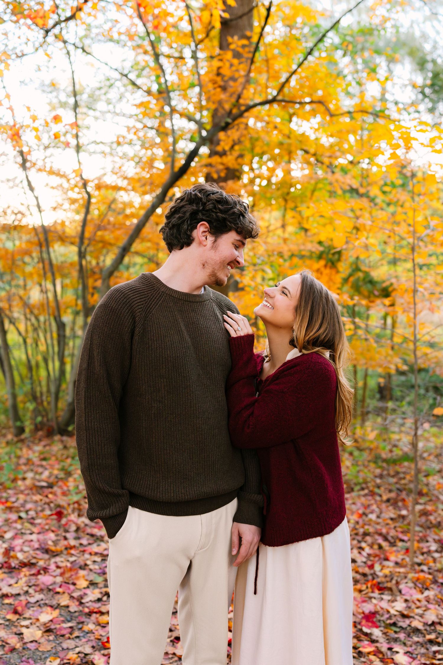 A couple shares tender glances during peak fall foliage engagement session at the Arnold Arboretum in Boston Massachusetts