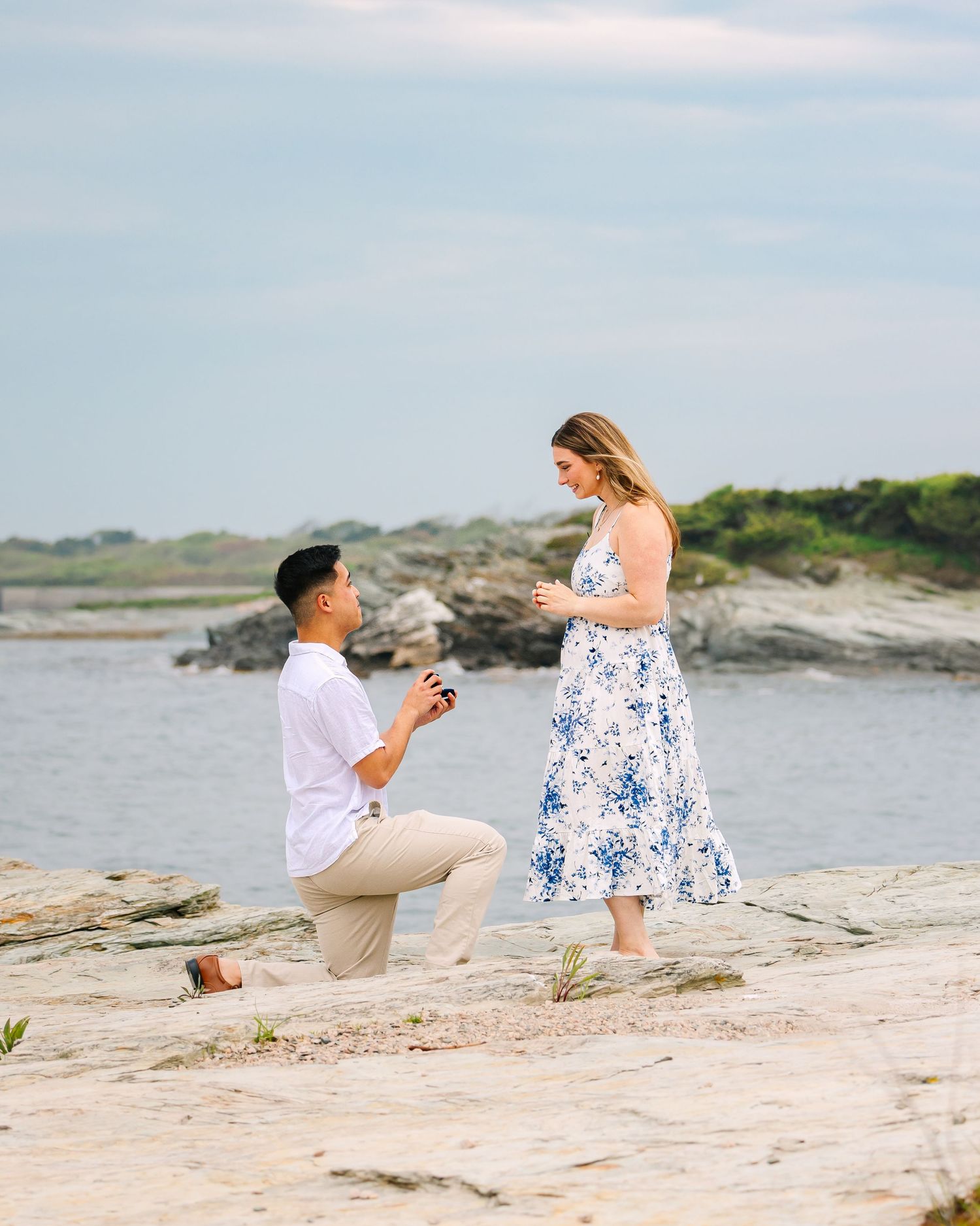 Couple shares an intimate surprise proposal on  rocky coastal cliff landscape on Ocean Drive in Newport Rhode Island