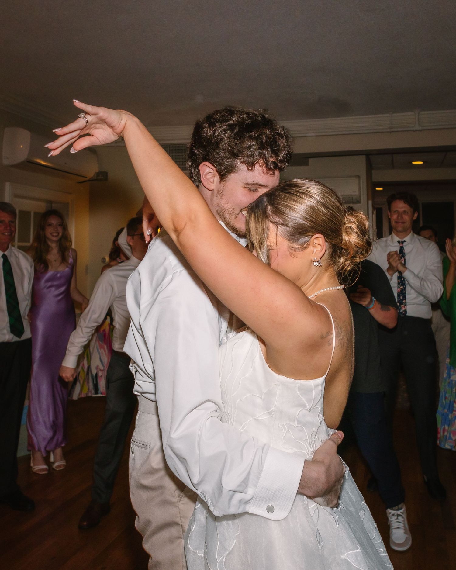 Bride and groom sharing a romantic dance embrace surrounded by guests at their wedding reception.
