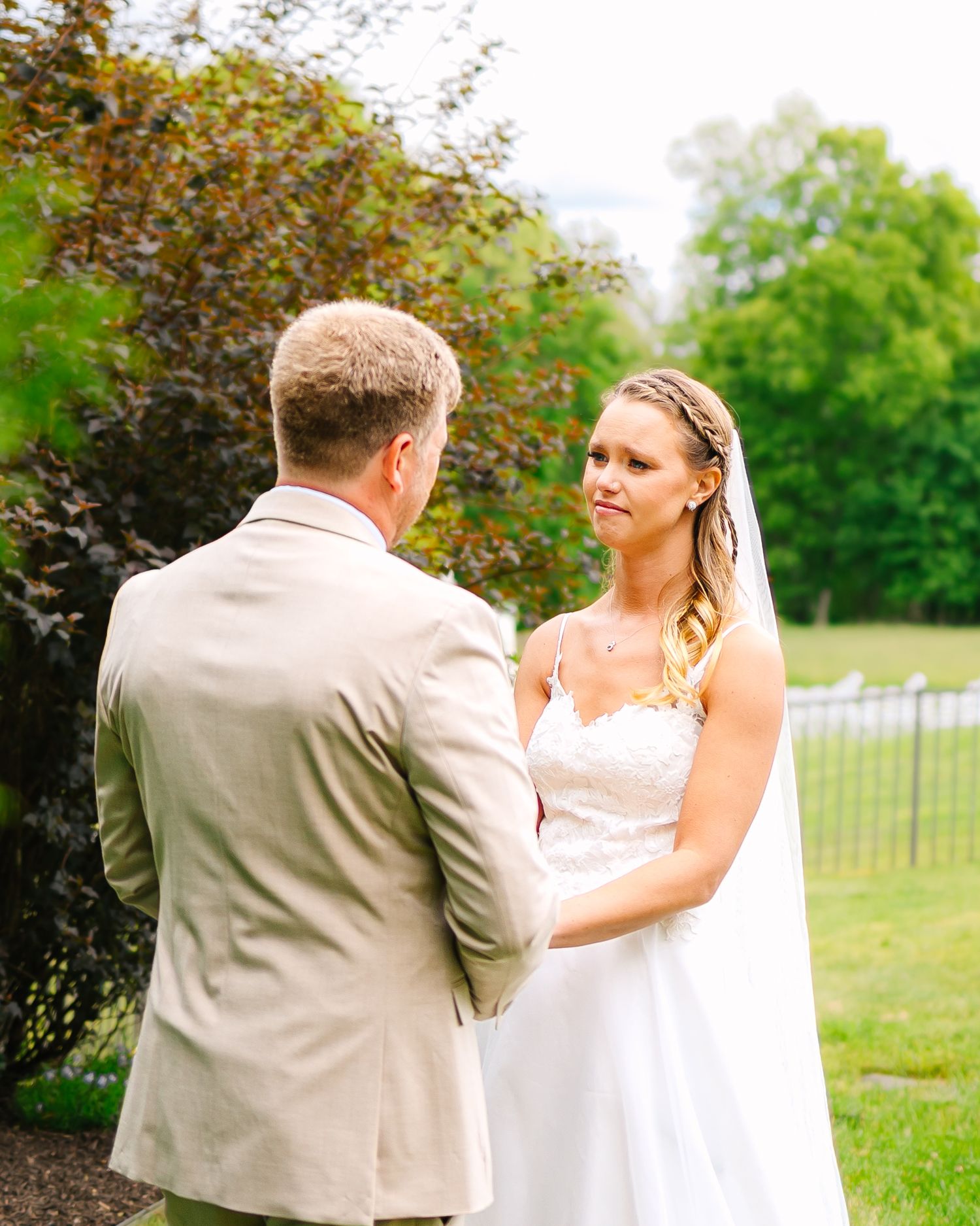 Couple dancing together on lush green lawn during outdoor wedding celebration in natural setting.