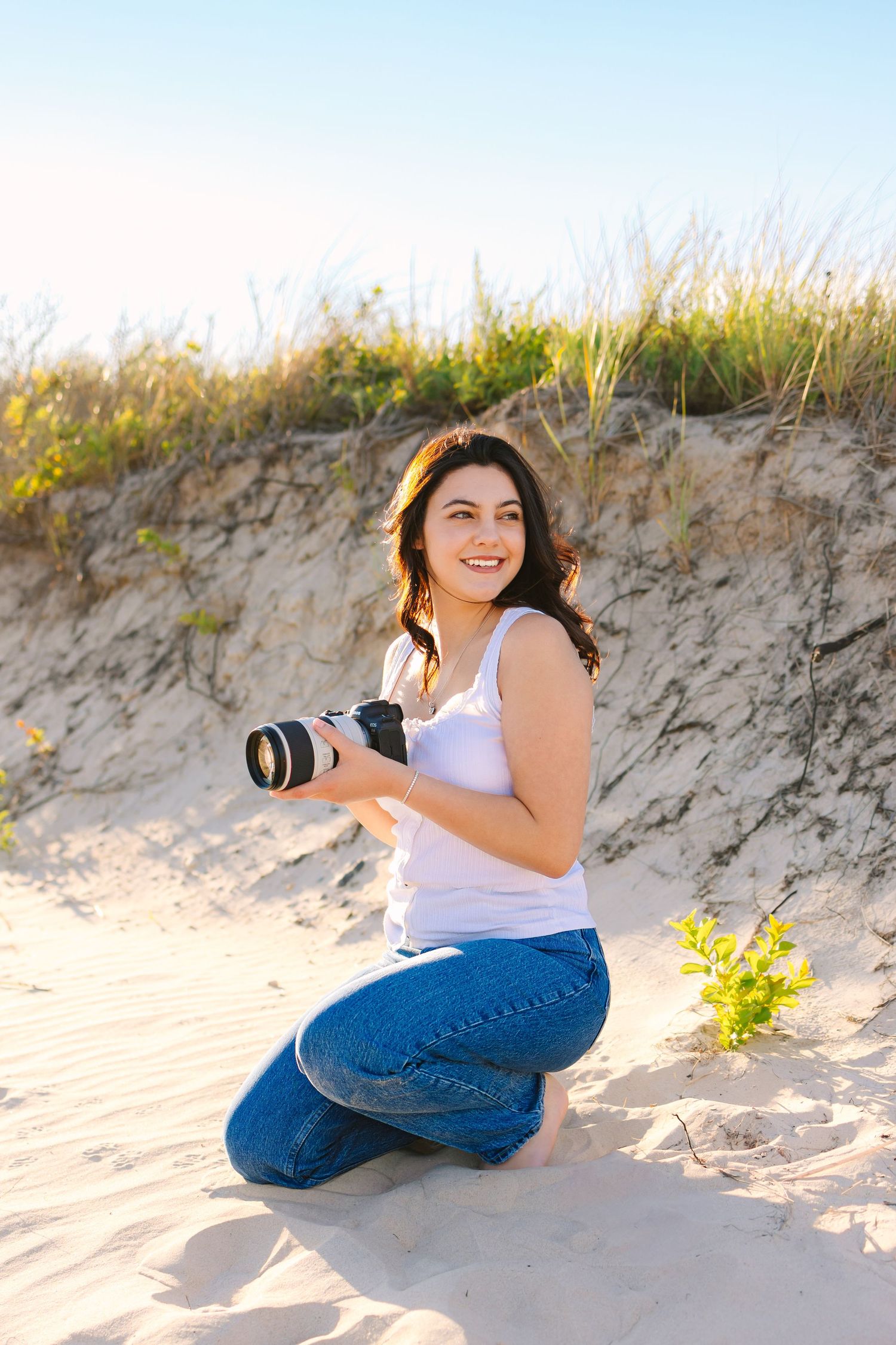 A photographer posing candidly holding camera by the sand dunes at sunset golden hour at Horseneck Beach in Westport, Massachusetts