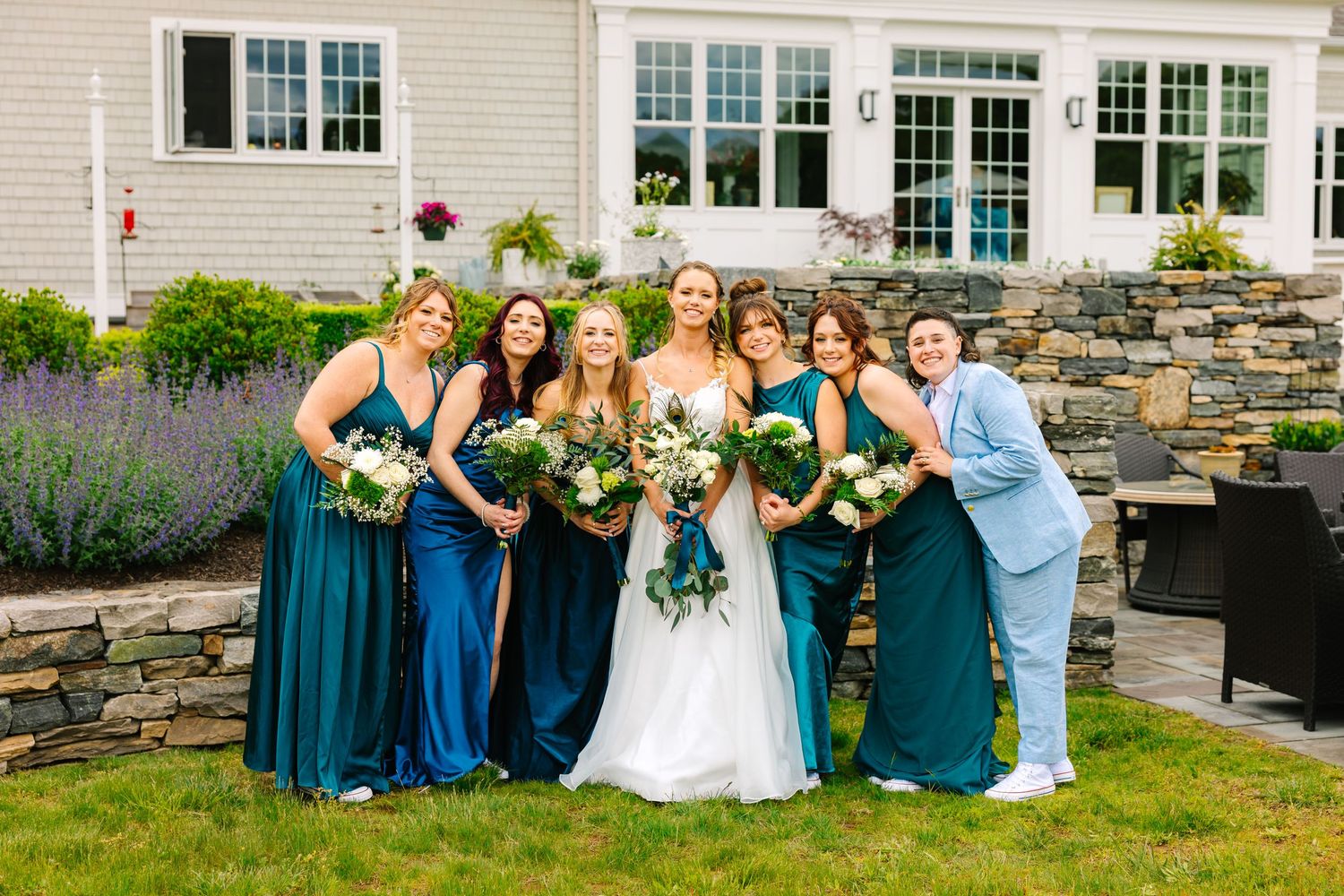 Groups gather in joyful celebration wearing elegant teal bridesmaid dresses and white wedding gown at outdoor venue.