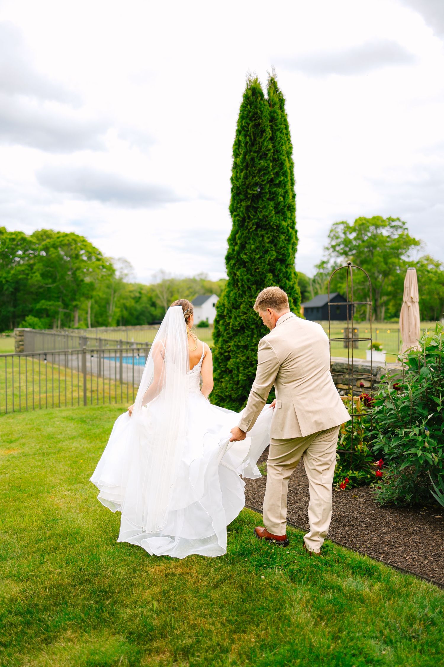 A bride and groom are photographed naturally walking inside after couples portraits at backyard wedding in Stonington, Connecticut