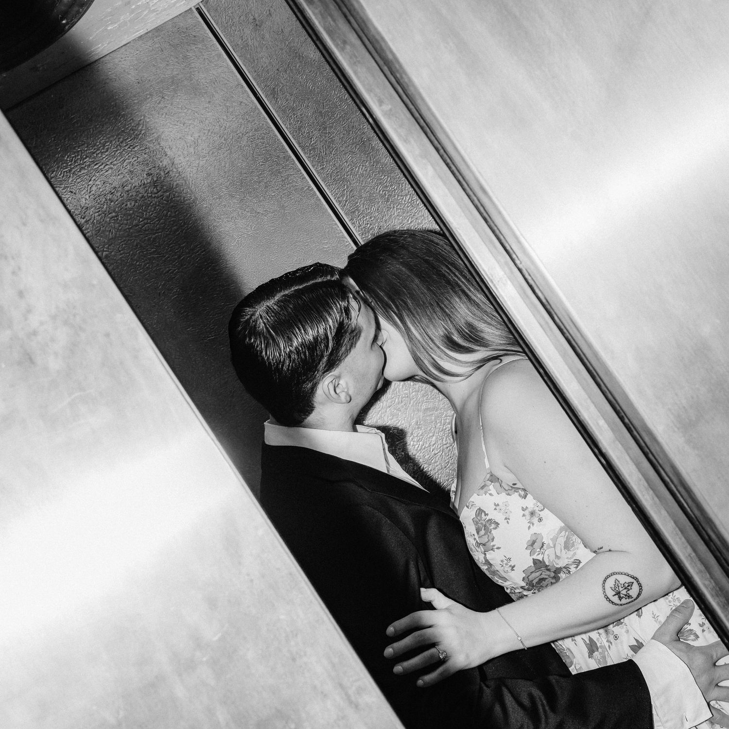 Black and white photo of couple kissing inside an elevator.