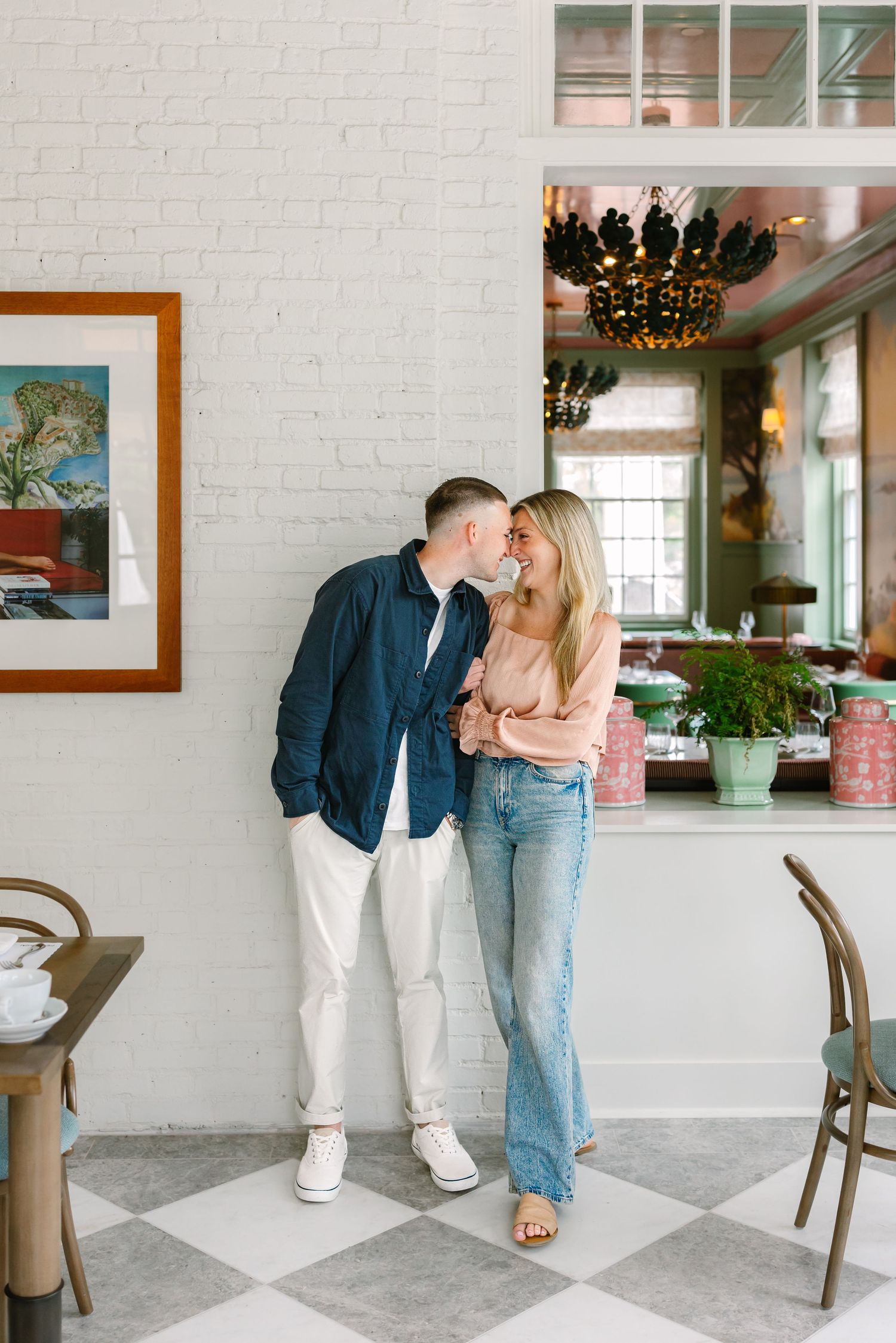 Couple sharing a tender kiss in a charming cafe with white brick walls and checkered floors.