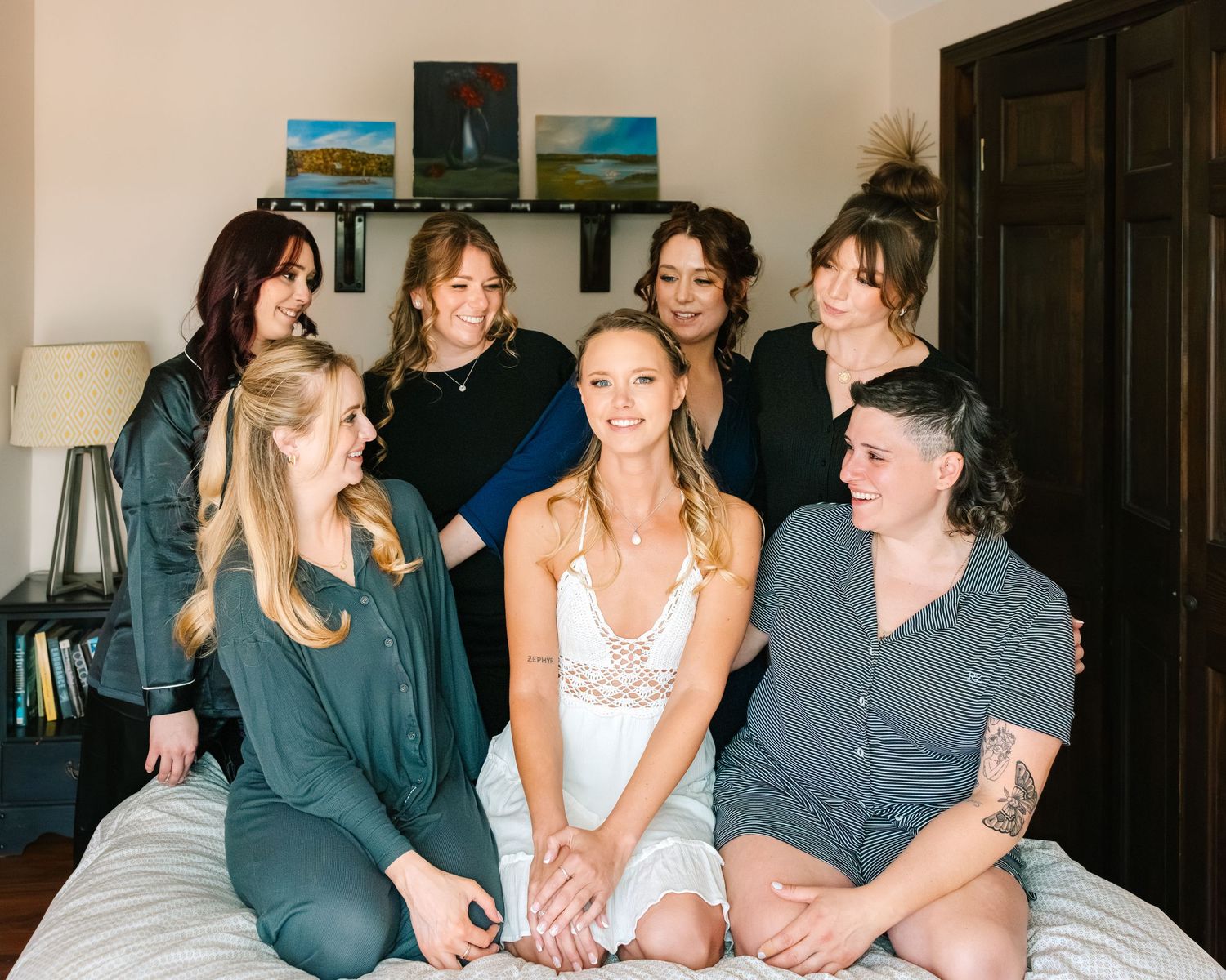 Group of friends lounging together and laughing on a couch during a casual indoor gathering.