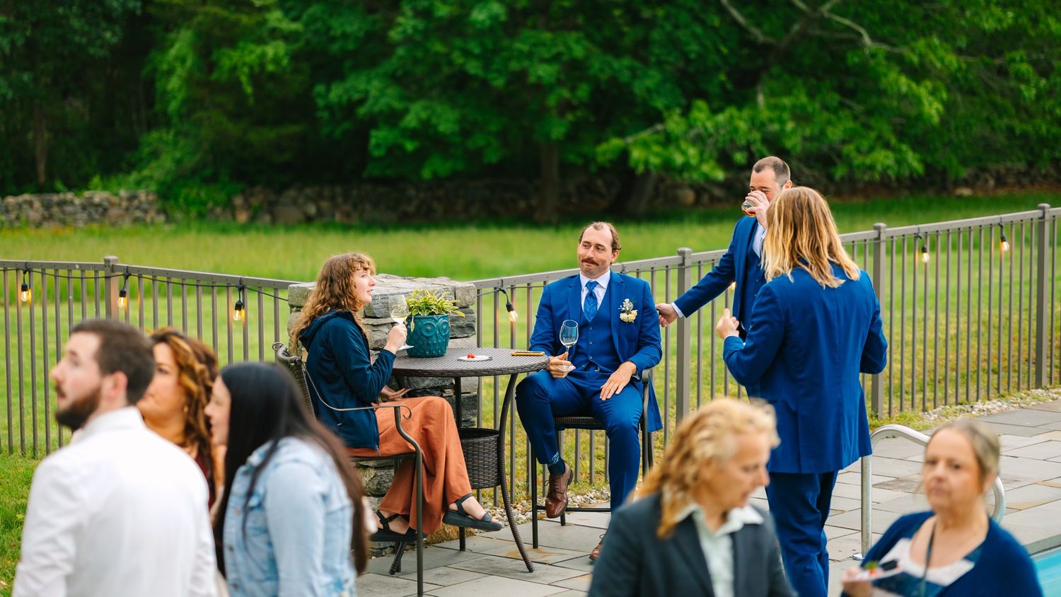 A group of people in blue uniforms gather outdoors for a casual event on a sunny day.