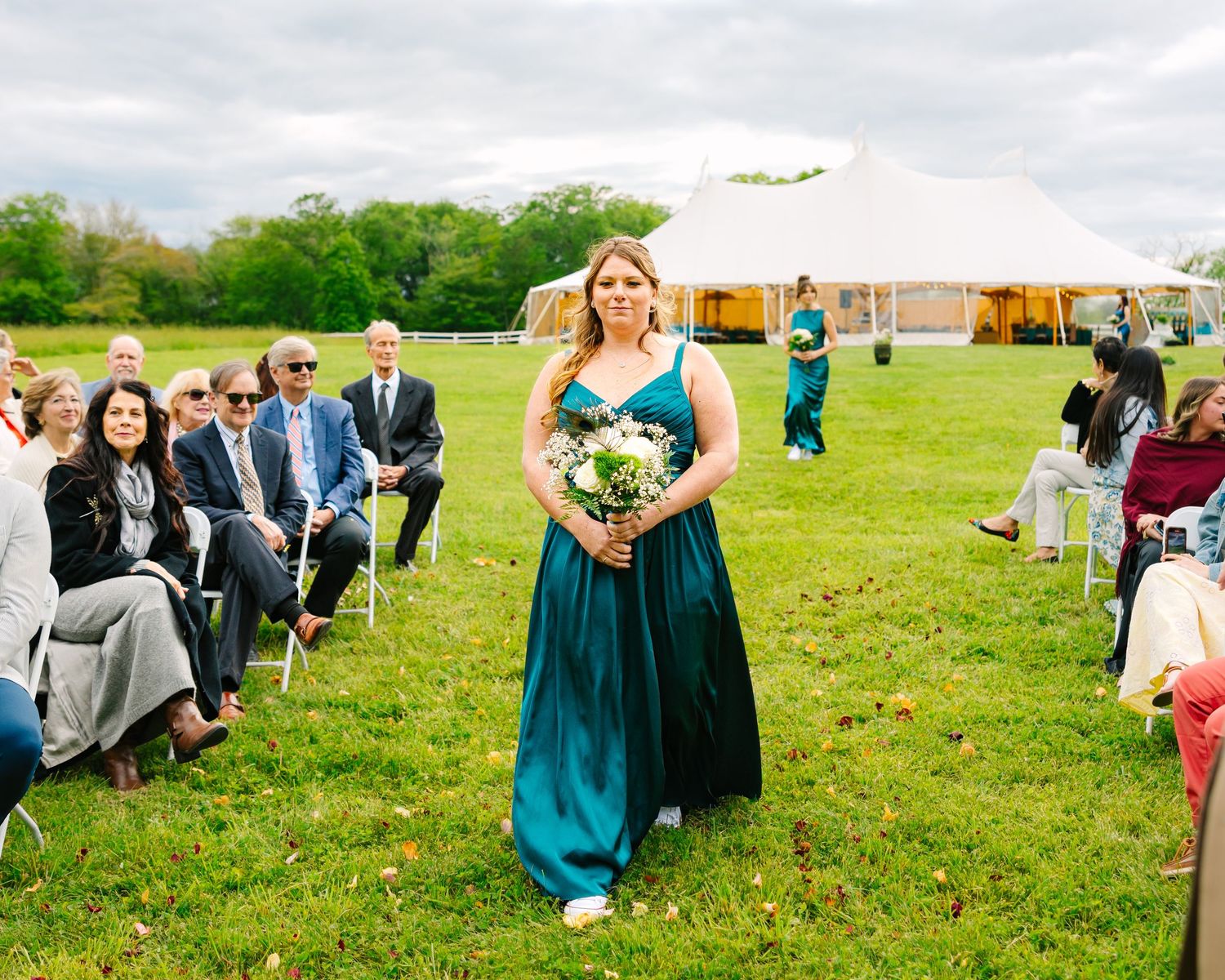 Panoramic view of an outdoor wedding ceremony on a green lawn with guests seated in white chairs.