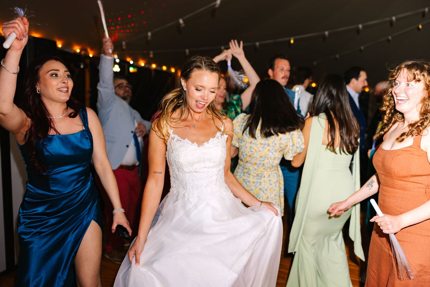 Bride and her guests dancing and celebrating at a lively wedding reception with string lights overhead in New London County Connecticut
