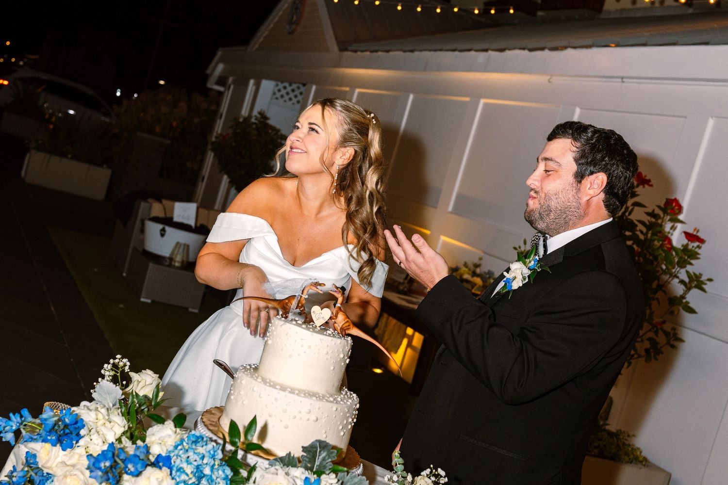A bride and groom candidly cut their wedding cake during wedding reception at The Regatta Place venue in Newport, Rhode Island