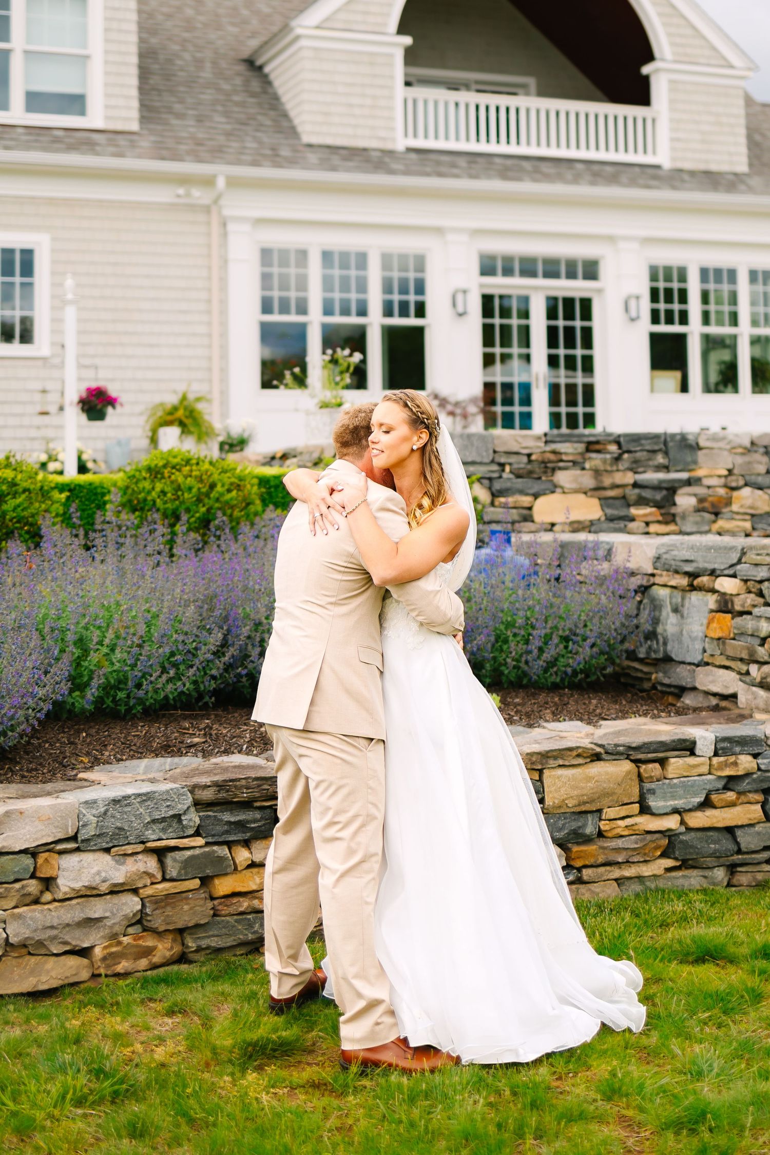 Light beige colored stone wall provides a romantic backdrop for a couple's special moment at an outdoor garden venue.