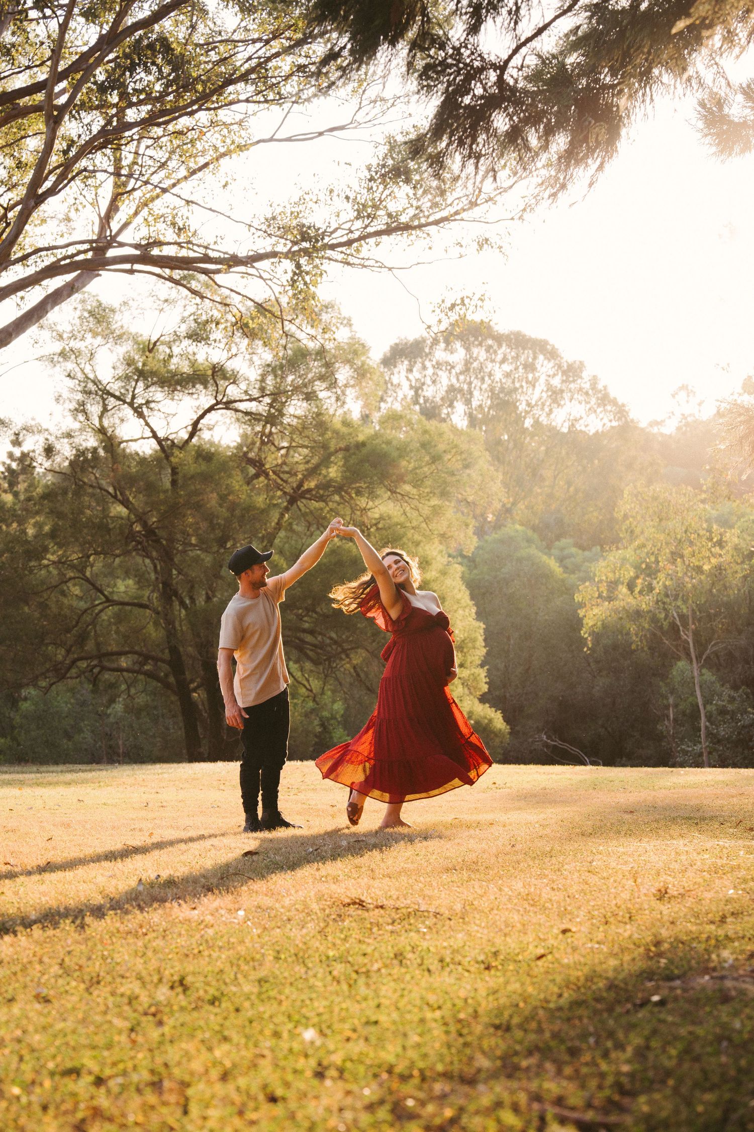 Couple dancing in the golden light during their maternity session