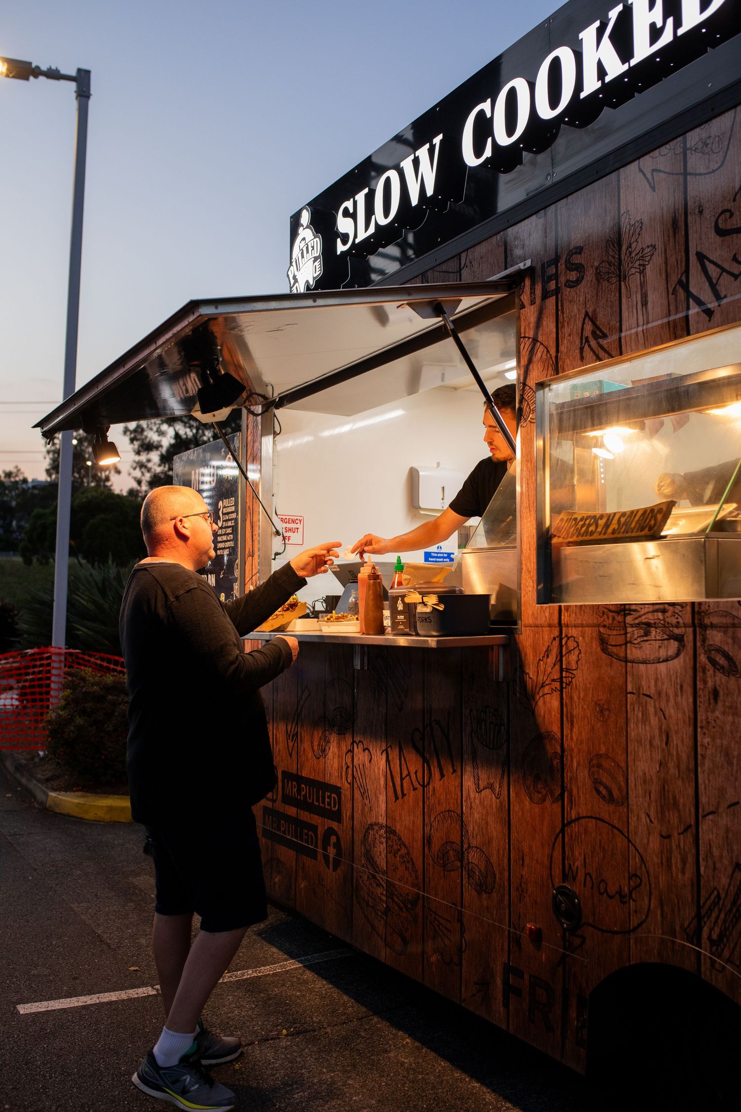 Food truck vendor serving a customer during a lively outdoor community event