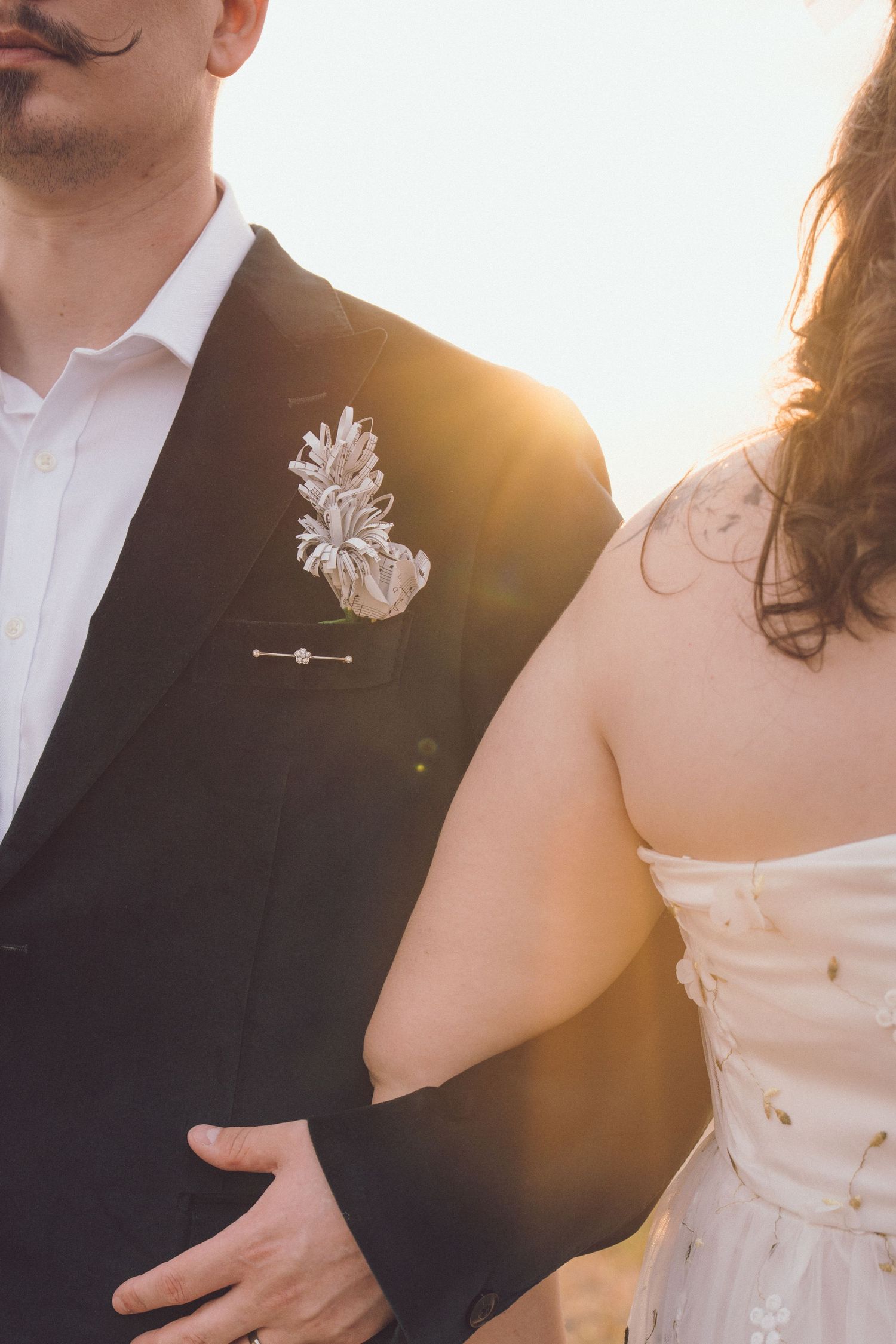 Bride and groom linking arms while walking together at sunset on their wedding day.
