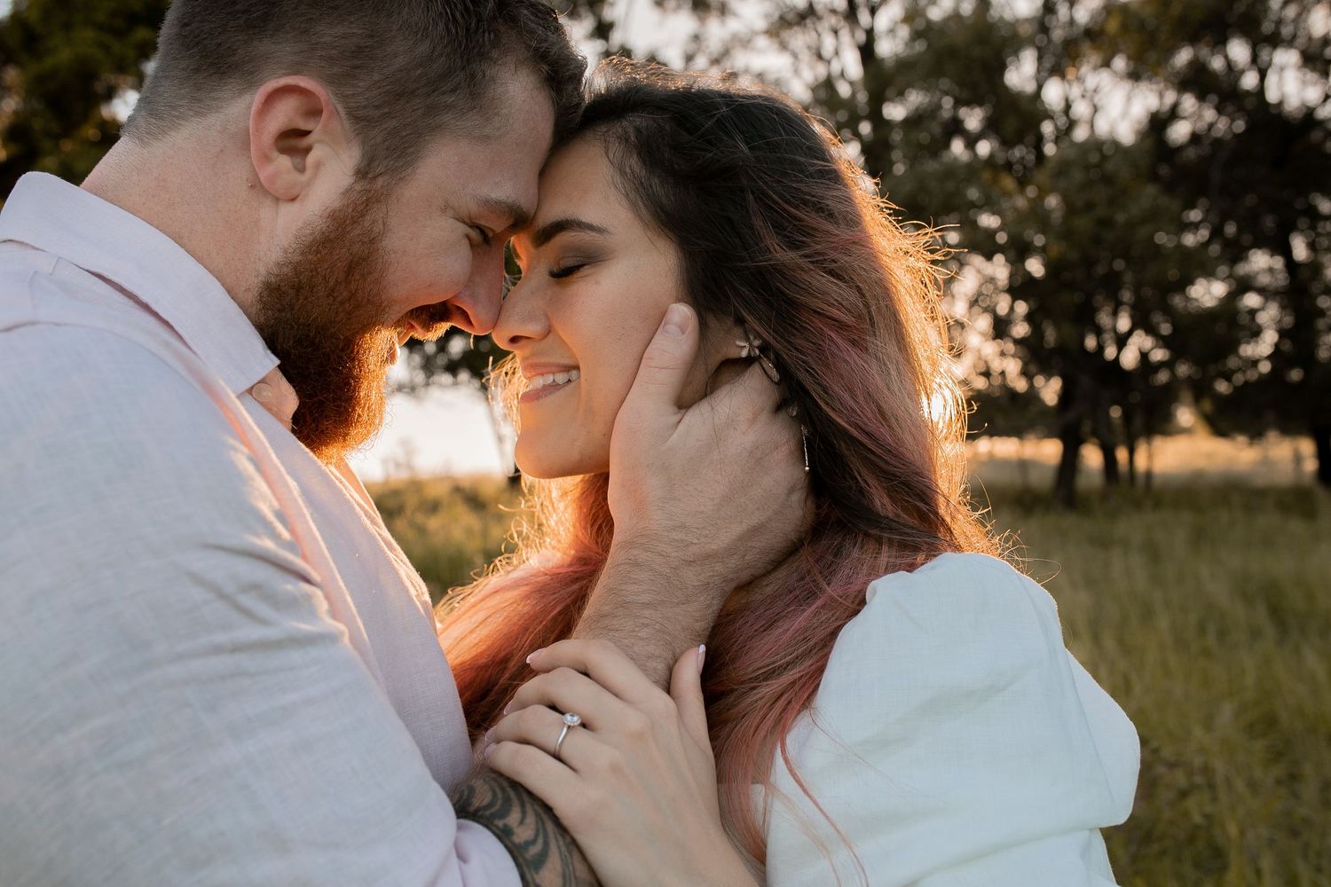 Engaged couple smiling with their foreheads together during a golden hour engagement photography session.
