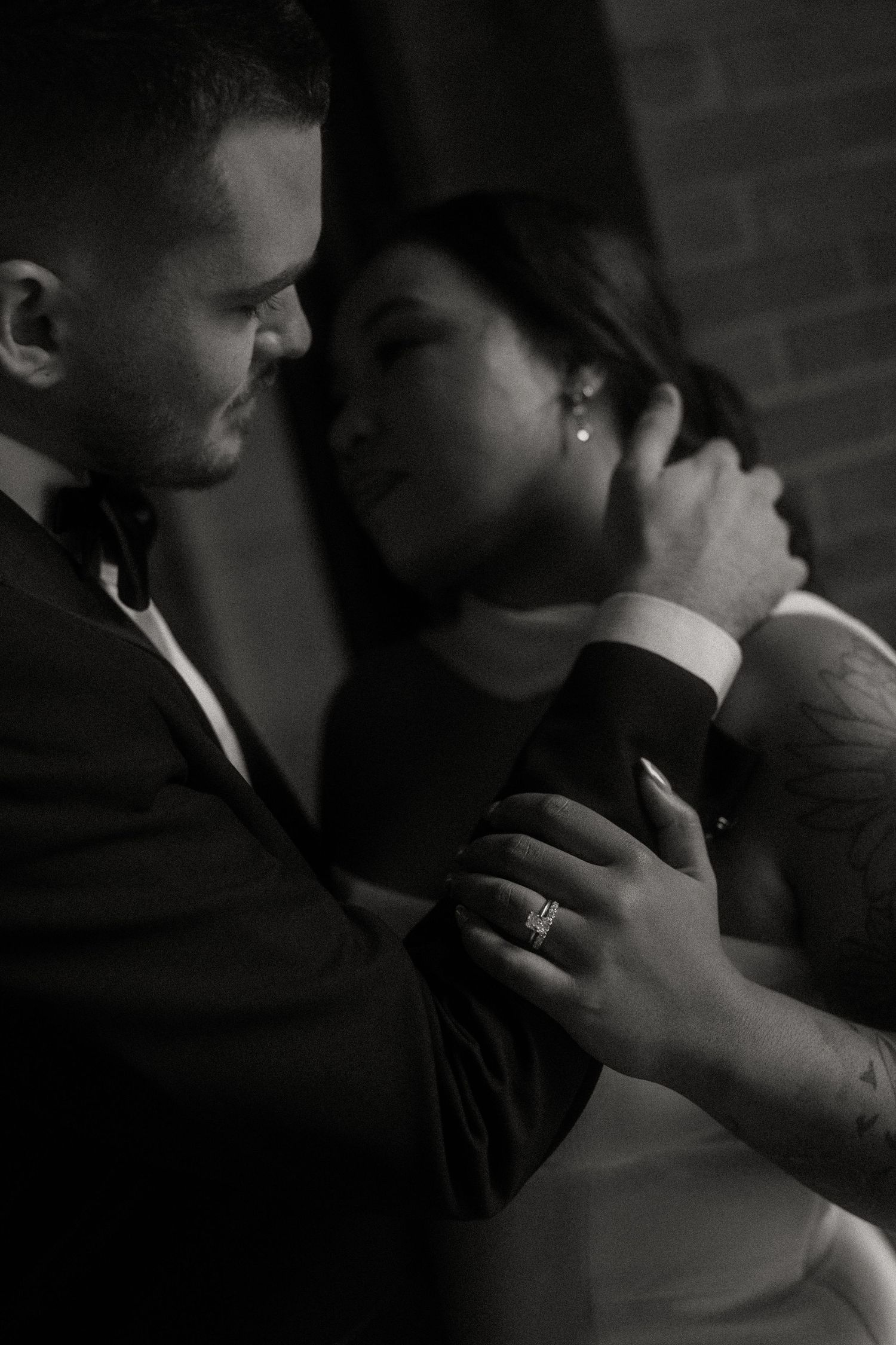 Black and white close-up of groom tenderly holding brides face during emotional wedding moment.