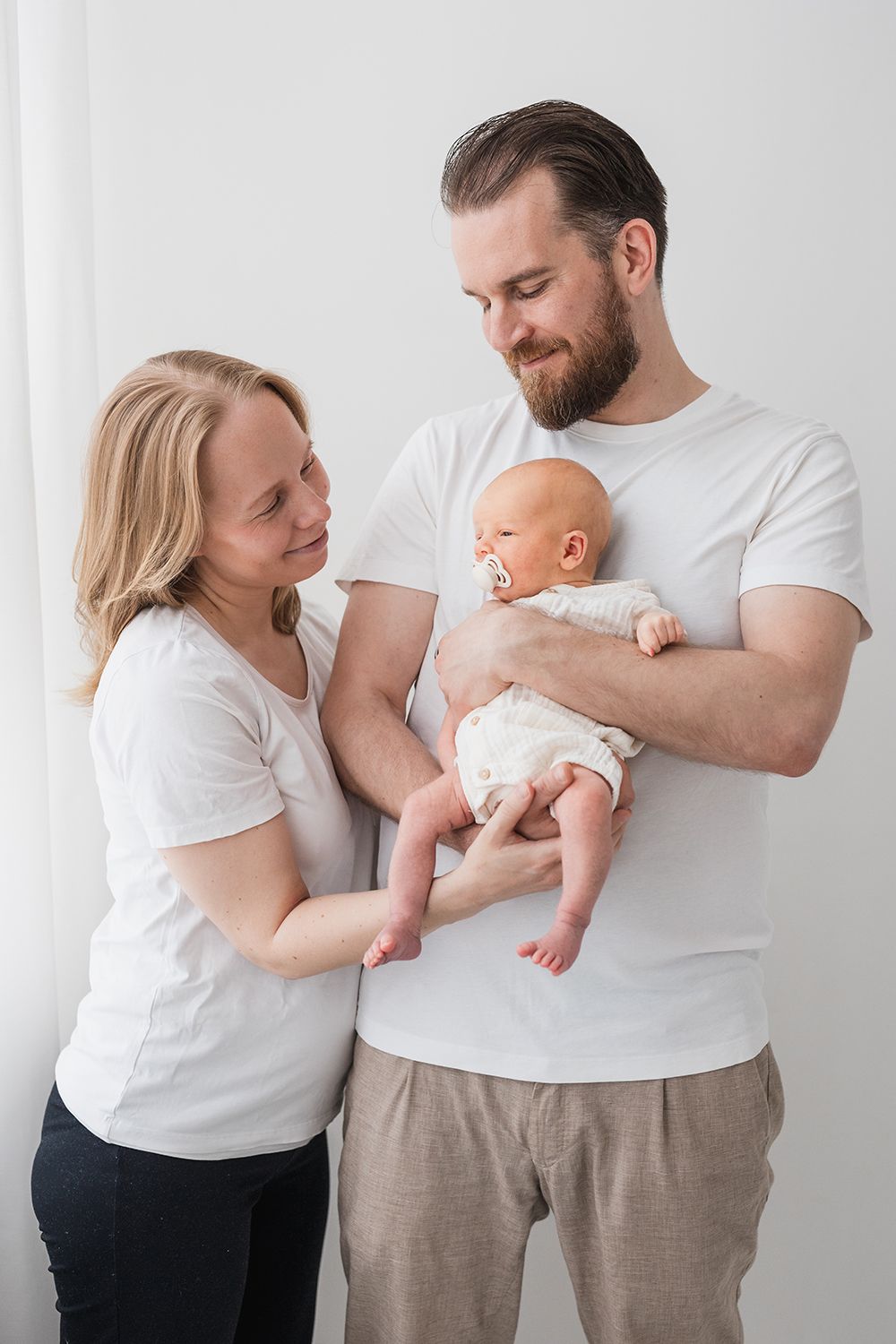 Mother and a father holding a newborn baby in a family photoshoot.