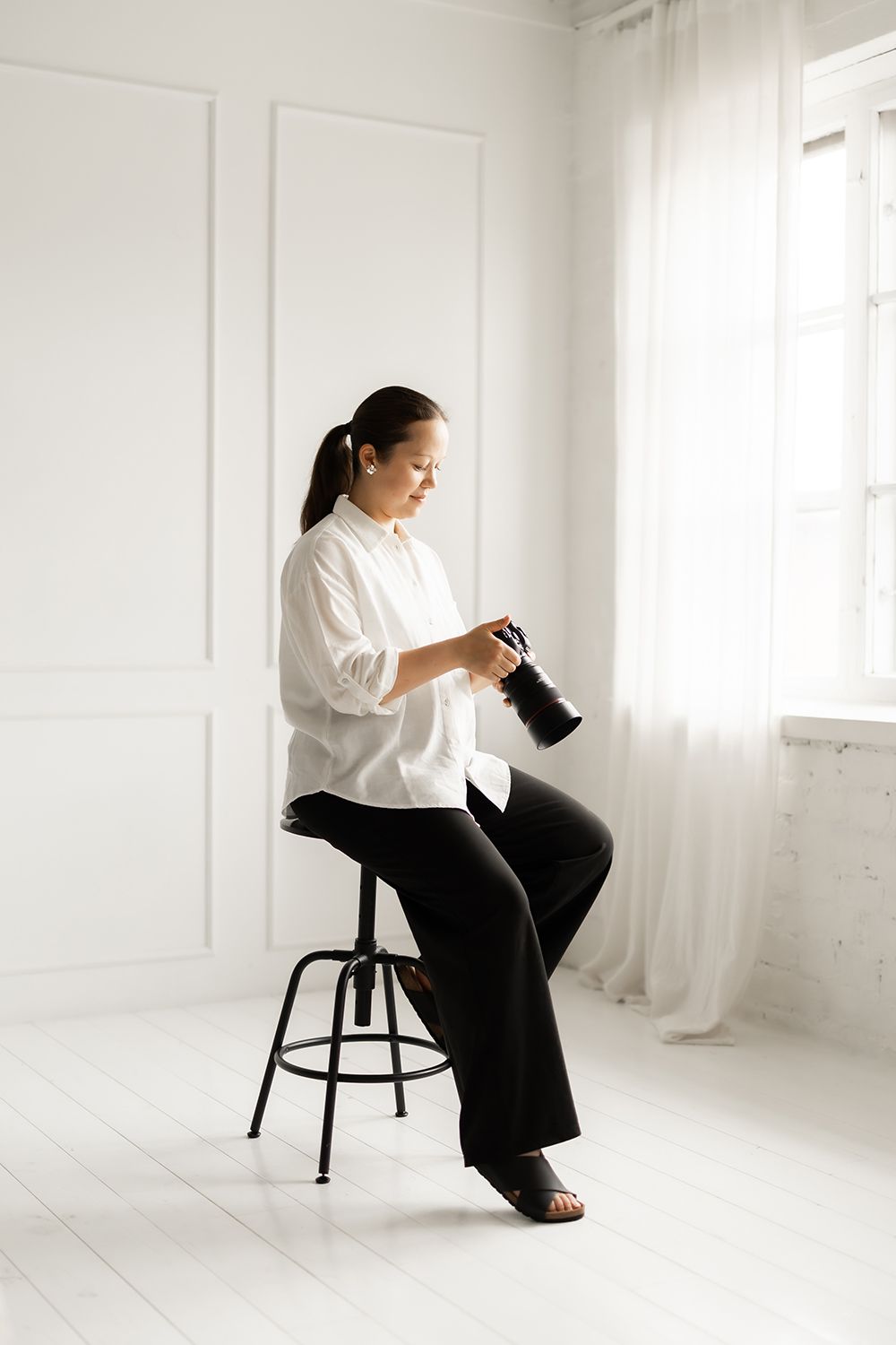 A woman sitting on a stool and holding a camera.