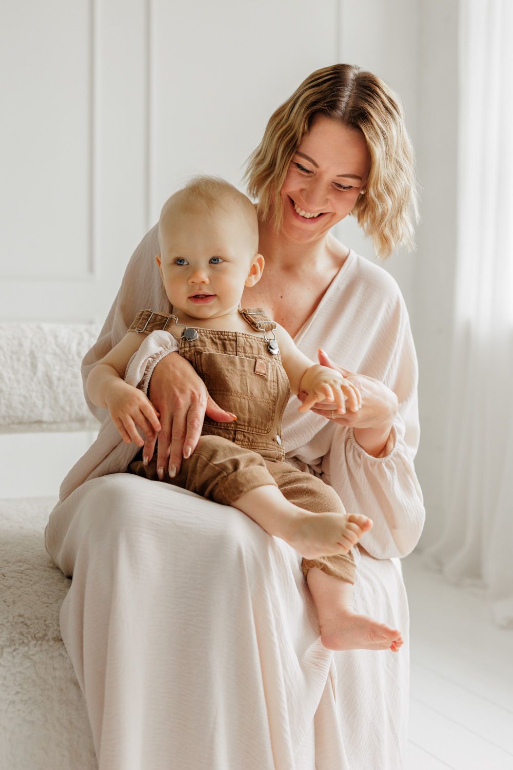 A mother sitting on a sofa and holding her baby boy.