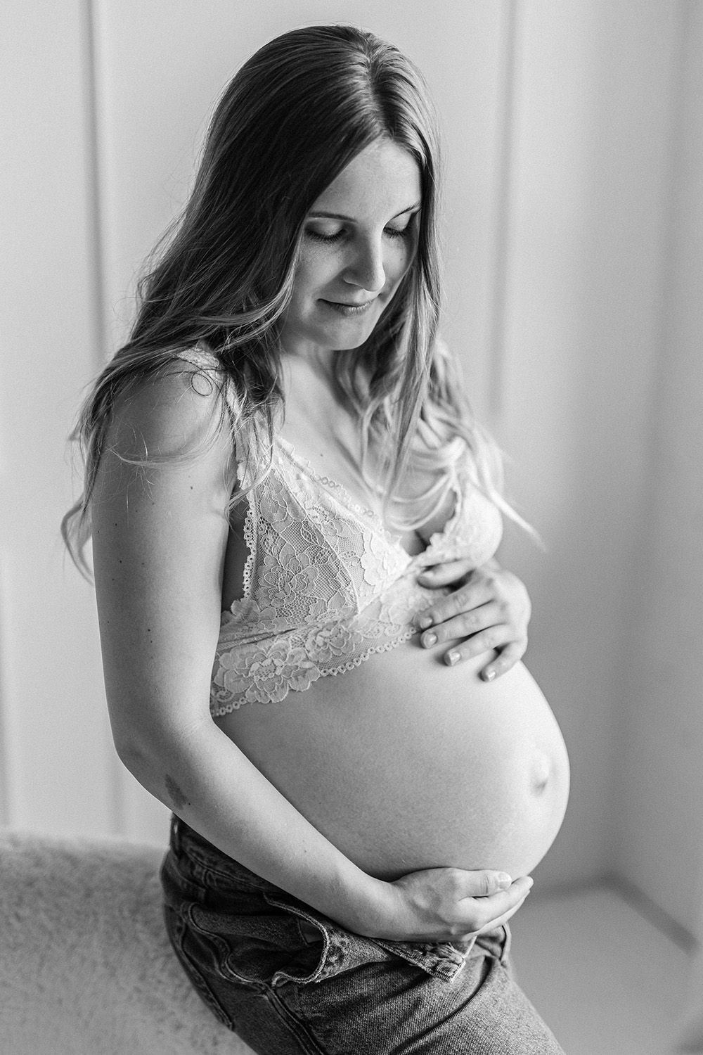 An expecting mother holding a baby bump. Black and white photograph.