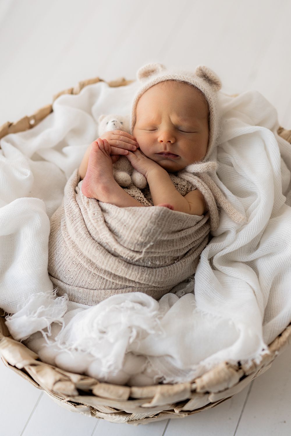 A newborn baby wrapped in a fabric sleeping in a basked.