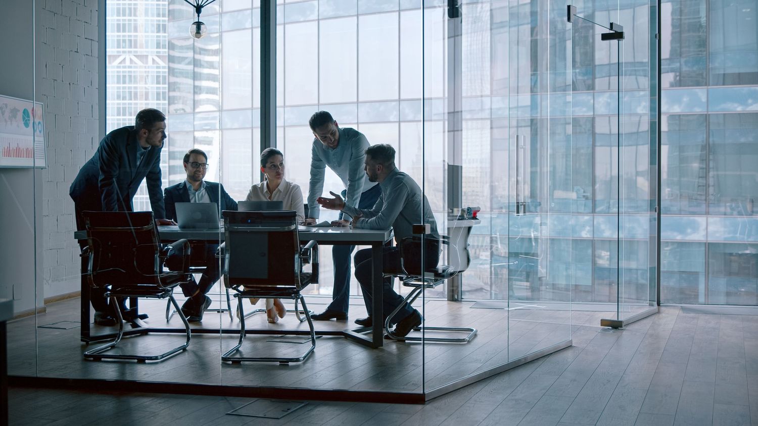 Business professionals collaborating in a modern glass conference room with city skyline views.
