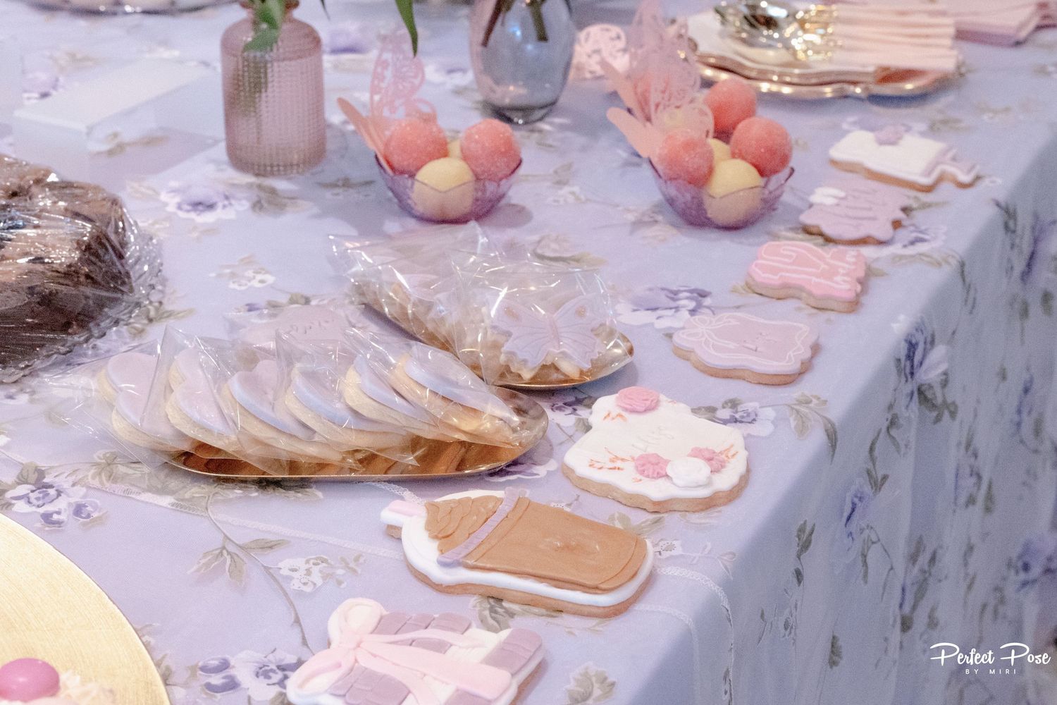 Elegant Easter dessert table with decorated sugar cookies, pastel eggs, and floral tablecloth for a spring celebration.