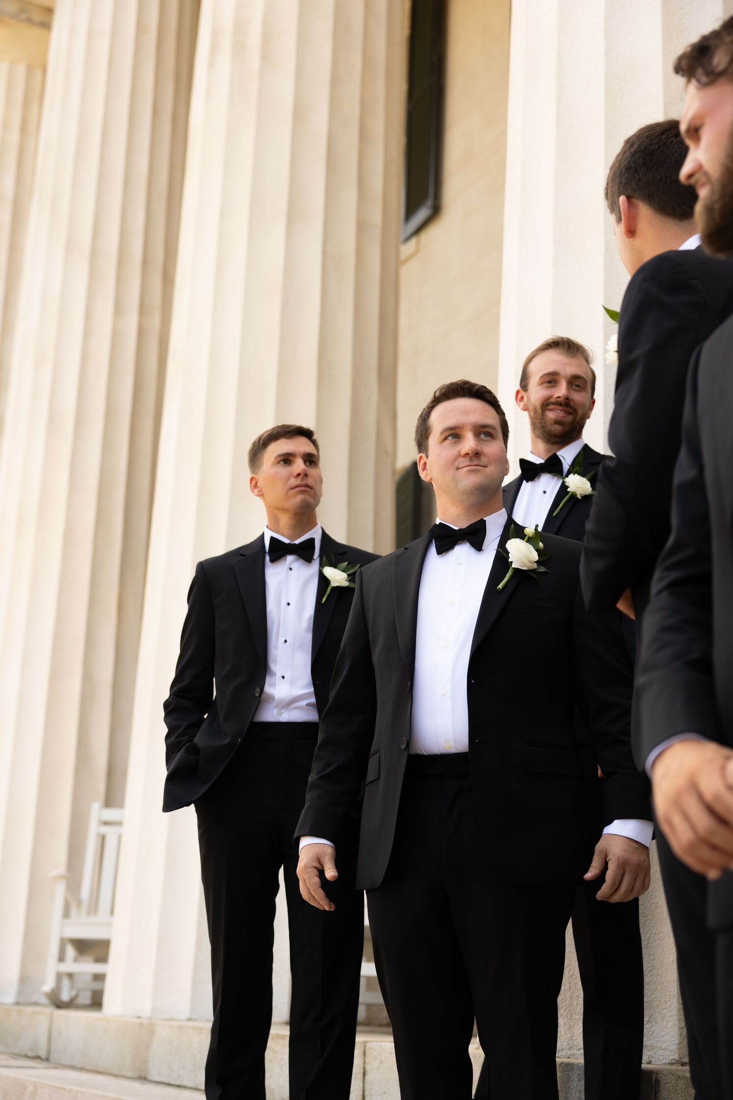 groomsmen standing on steps of estate with large columns