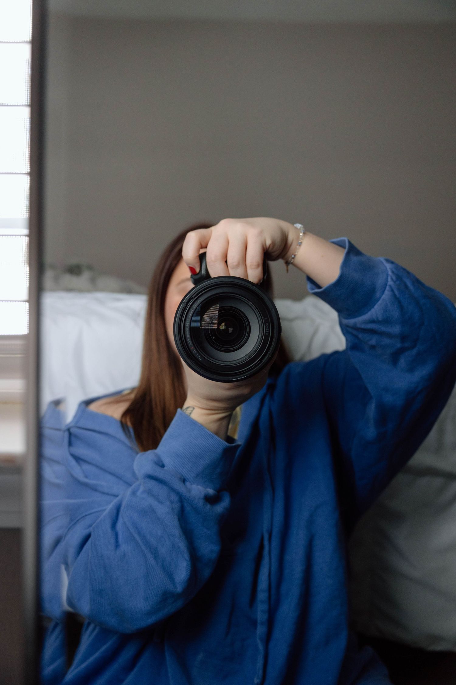 girl taking photo of self in mirror with large camera
