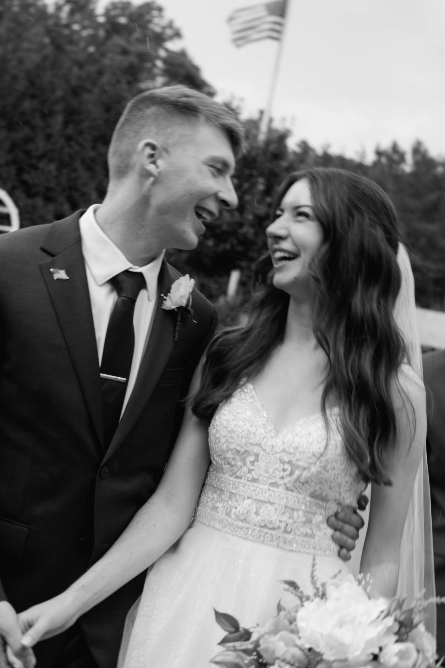 Bride and groom in black and white smiling and looking at each other.