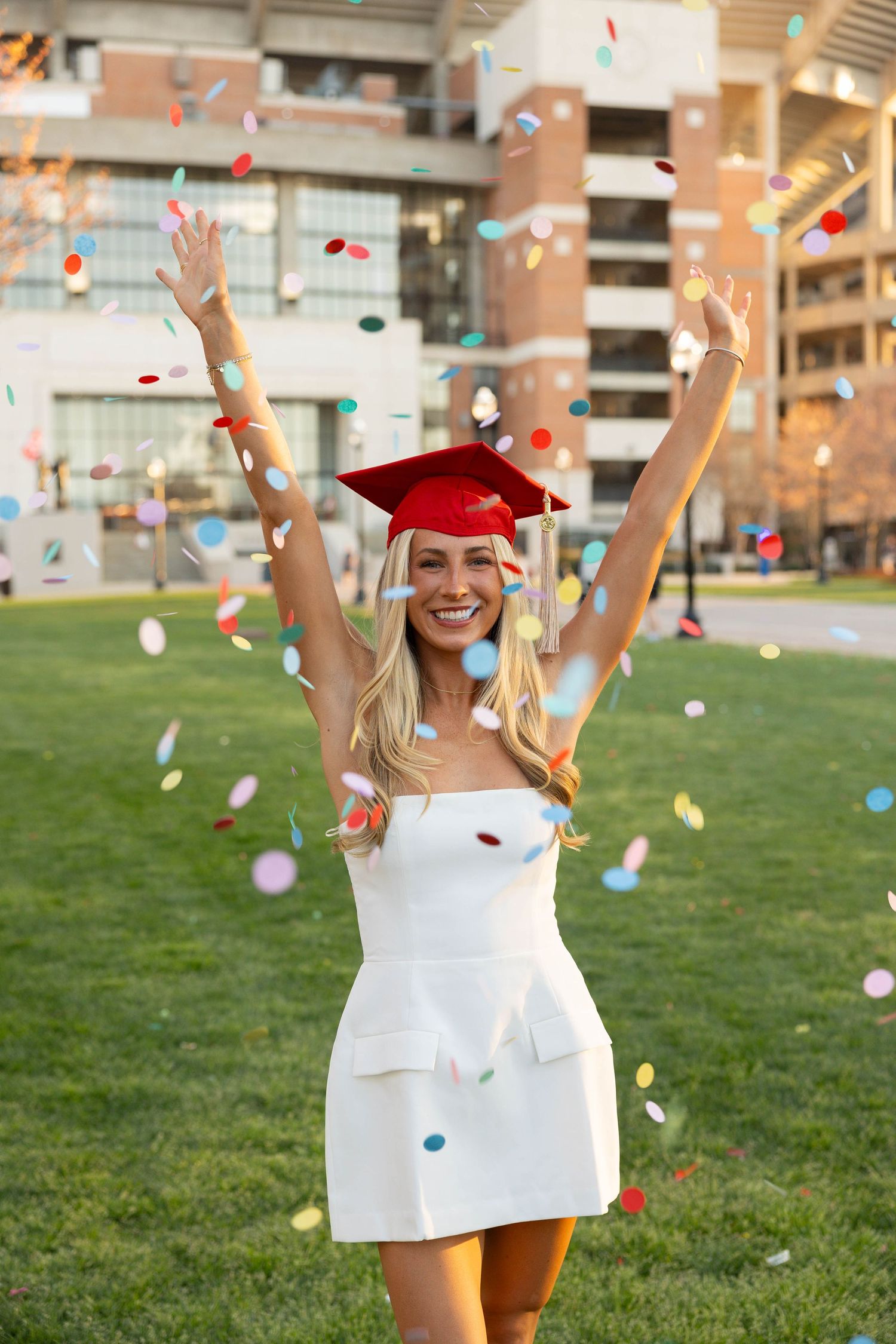 girl throwing confetti in a red graduation cap