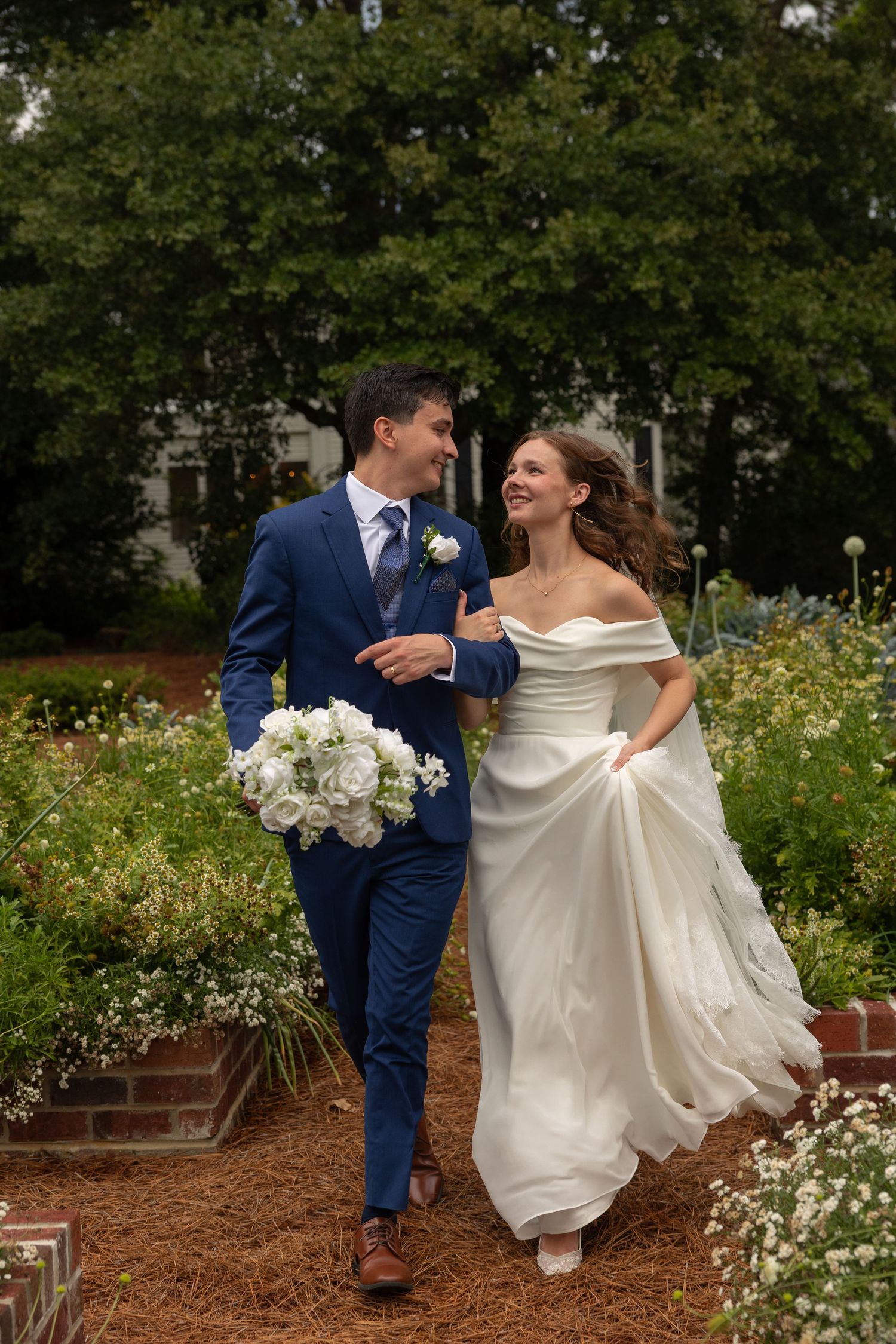 bride and groom running through garden looking at each other