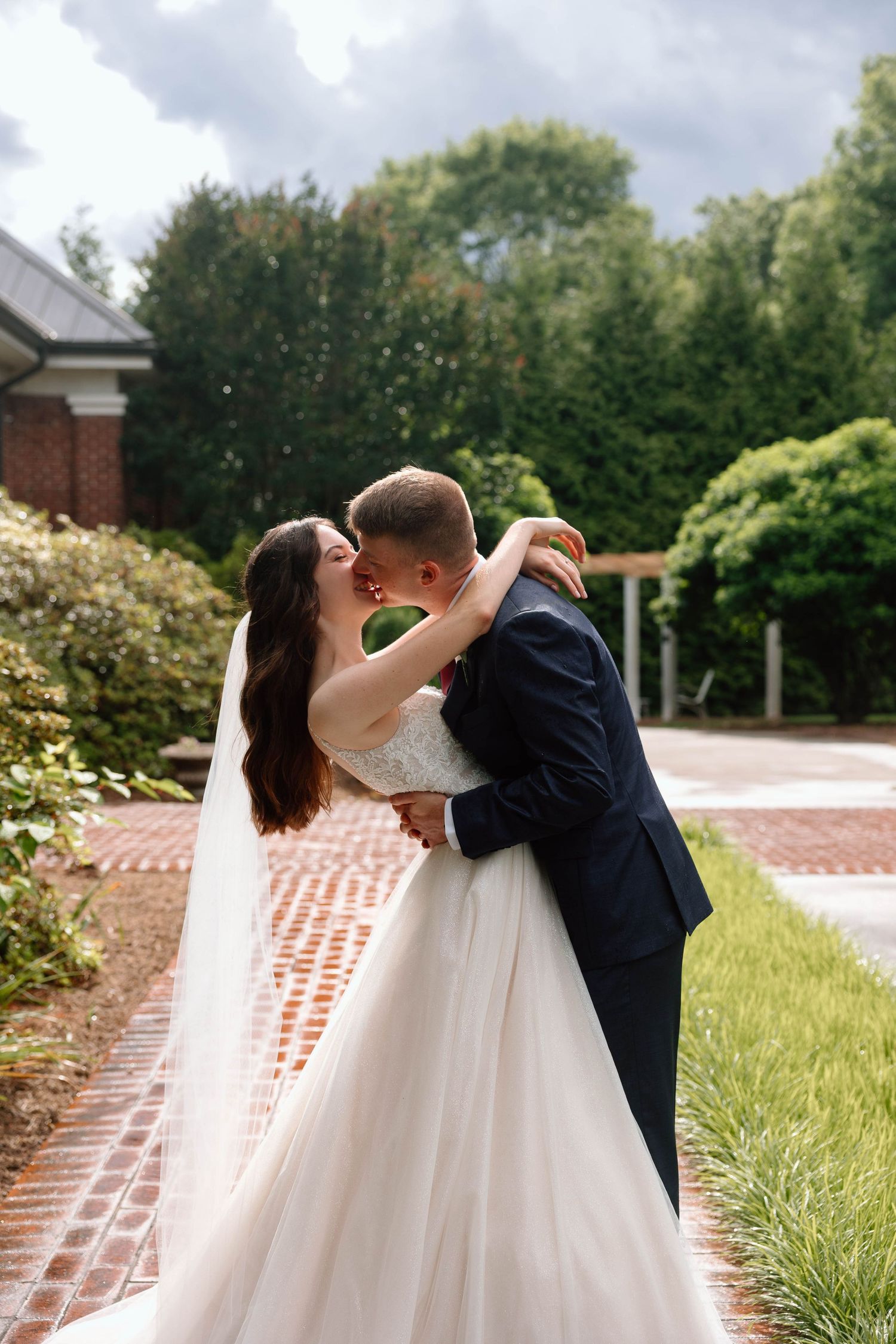 bride and groom kissing with sun beaming behind them
